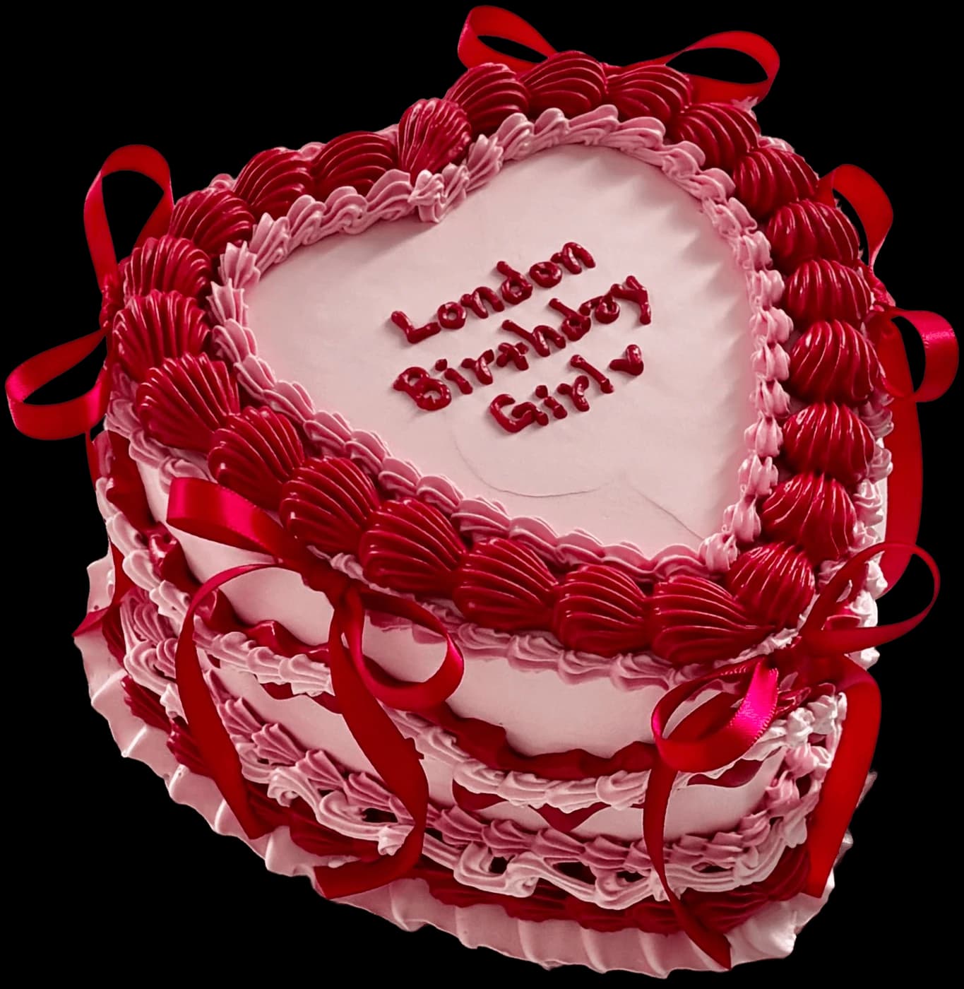 Pink and red heart-shaped birthday cake with piped shell borders and satin bows, handmade by Danine Cakes in Streatham