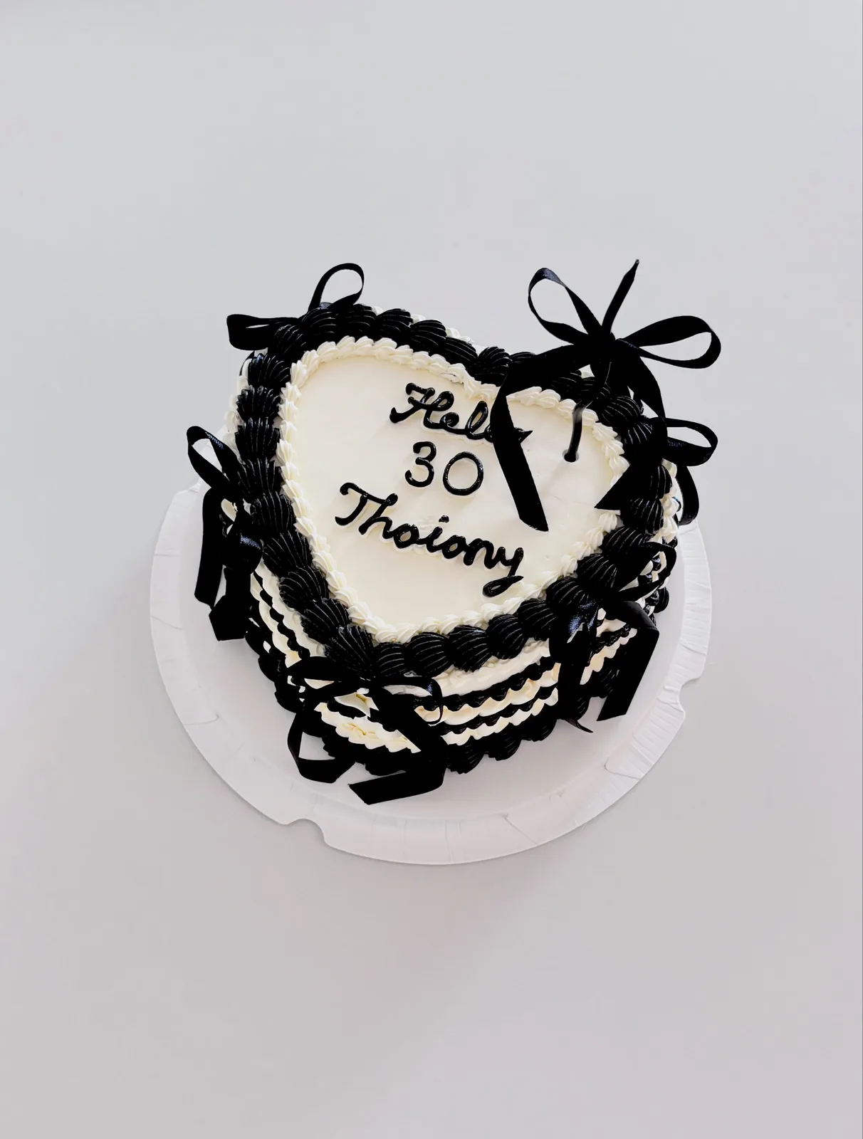 Black and white heart cake with bows and piped lettering, Korean-inspired custom cake handmade in Streatham, London