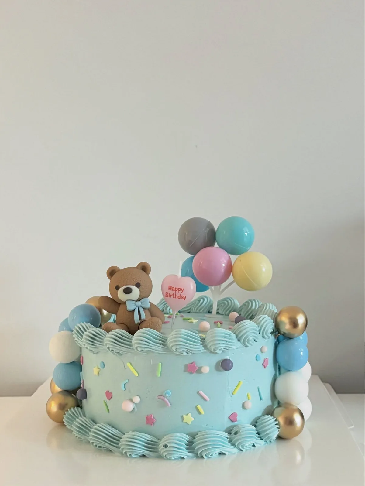 Blue cake with teddy bear and balloon toppers, bespoke celebration cake from Danine Cakes, South London