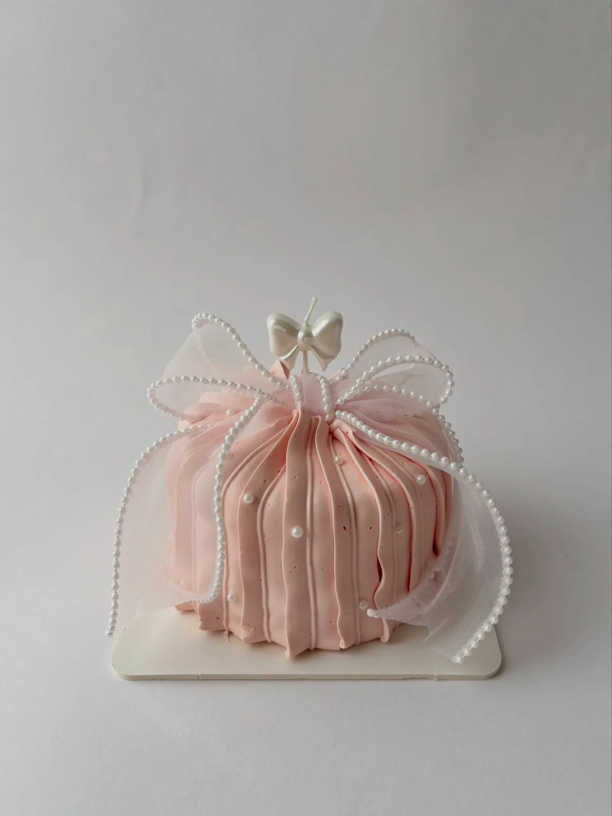 Blush pink piped dome cake with pearls and bow, handmade to order by Danine Cakes in Streatham, South London