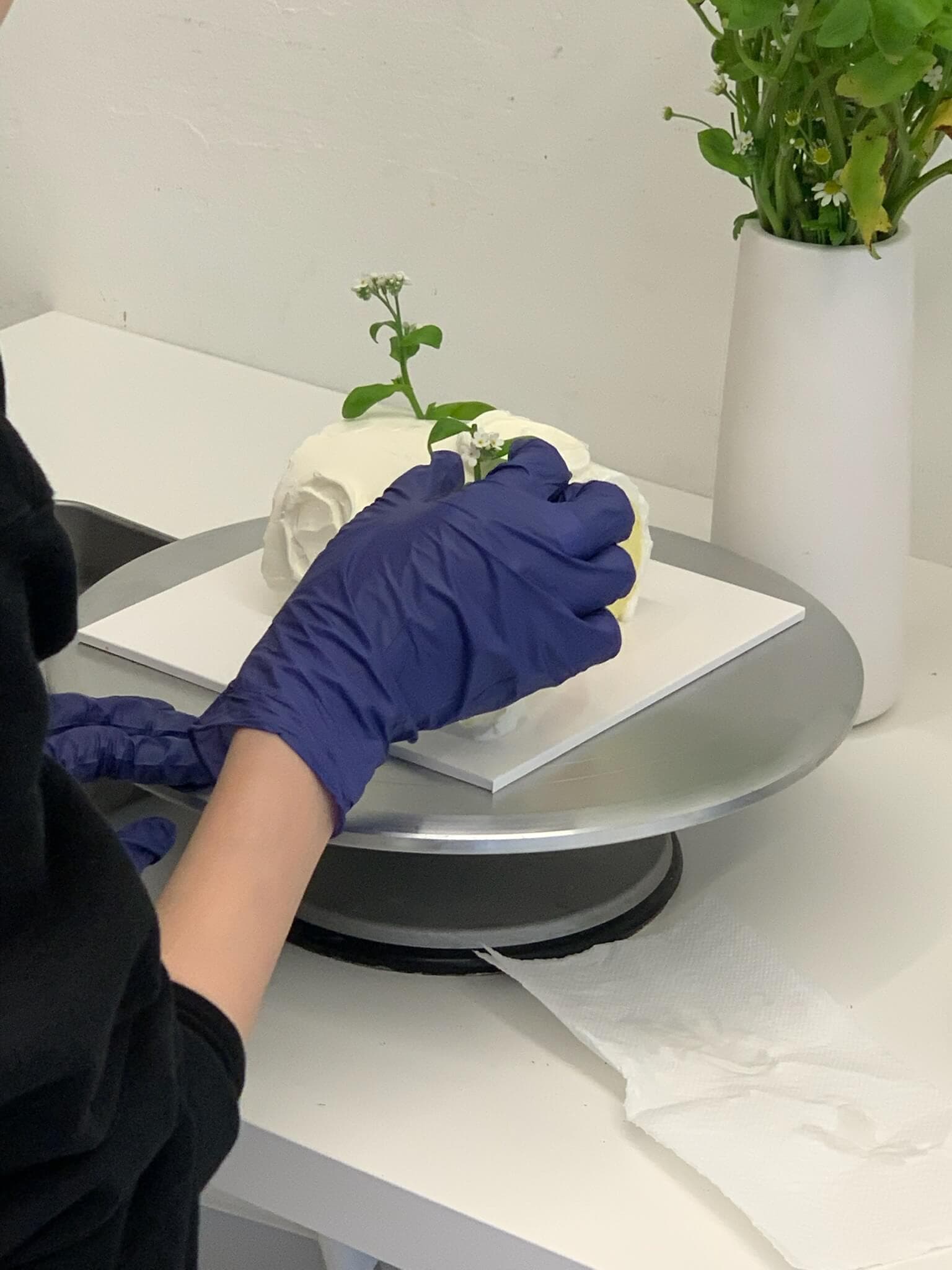 Cake decorating class in Streatham — smoothing buttercream on a fresh floral cake