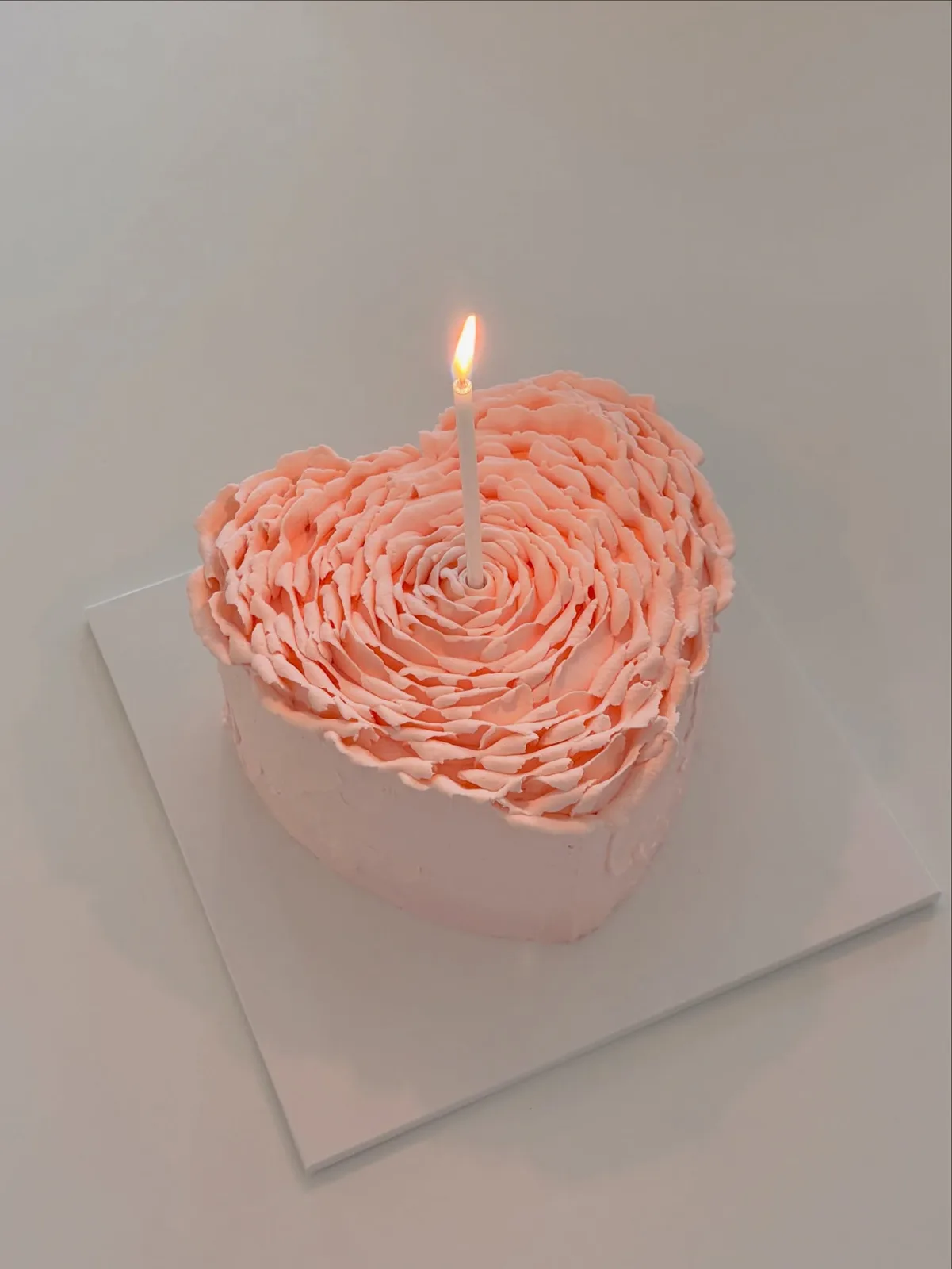 Coral piped rosette heart cake with candle, handmade to order by Danine Cakes in Streatham, South London
