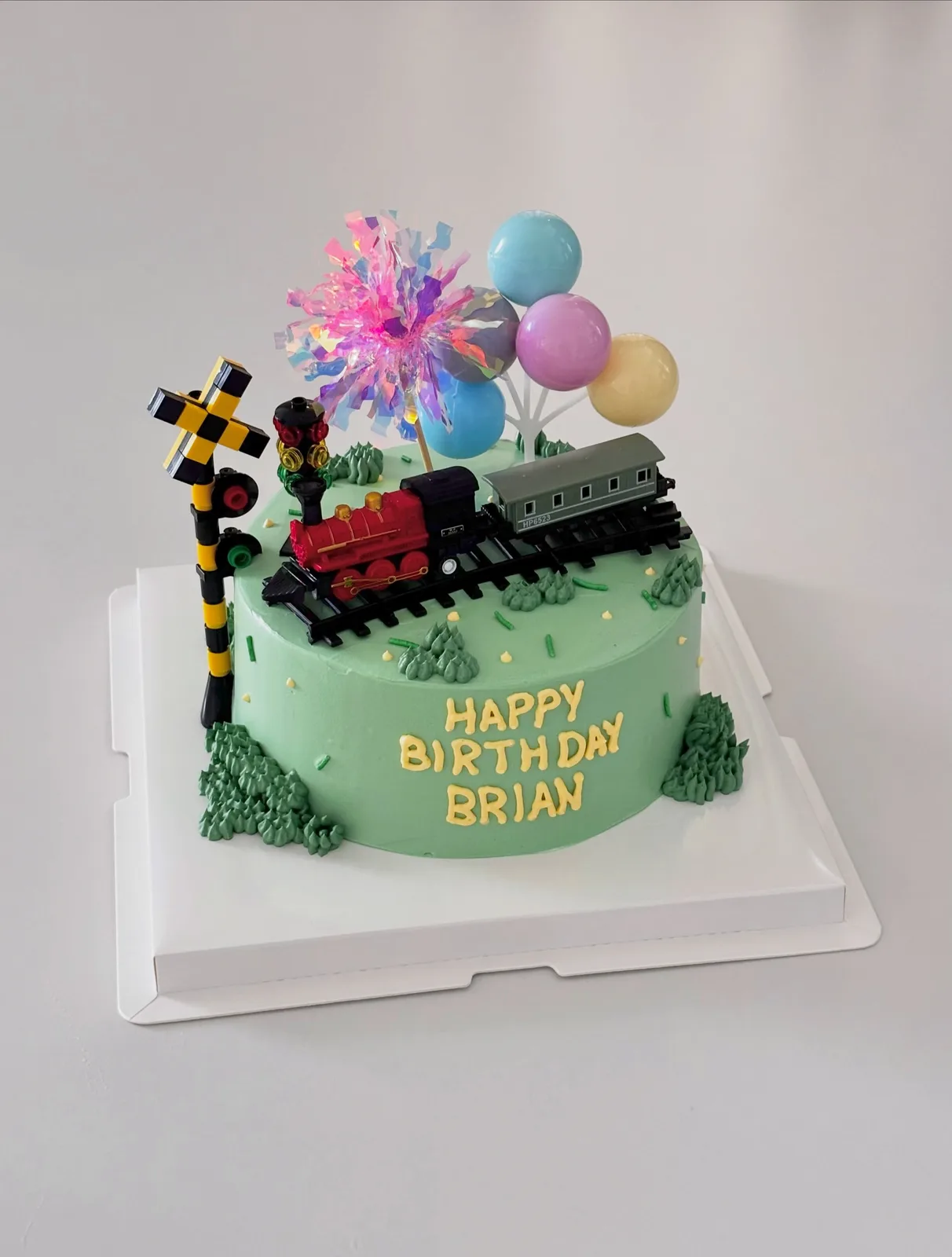 Green cake with train and balloon toppers, Korean-inspired custom cake handmade in Streatham, London