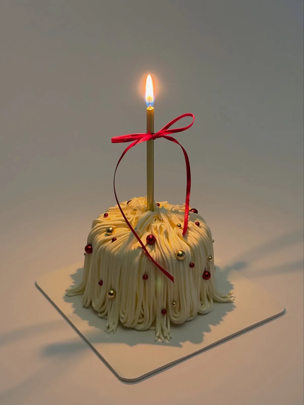 Green piped strand cake with red ribbon and tall candle, Korean-inspired custom cake handmade in Streatham, London