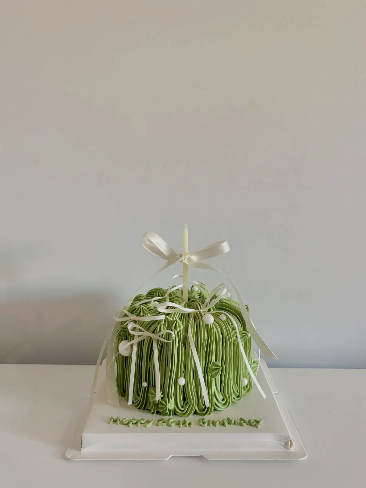 Green piped strand cake with white bow, custom cake made in Streatham SW16 - Danine Cakes