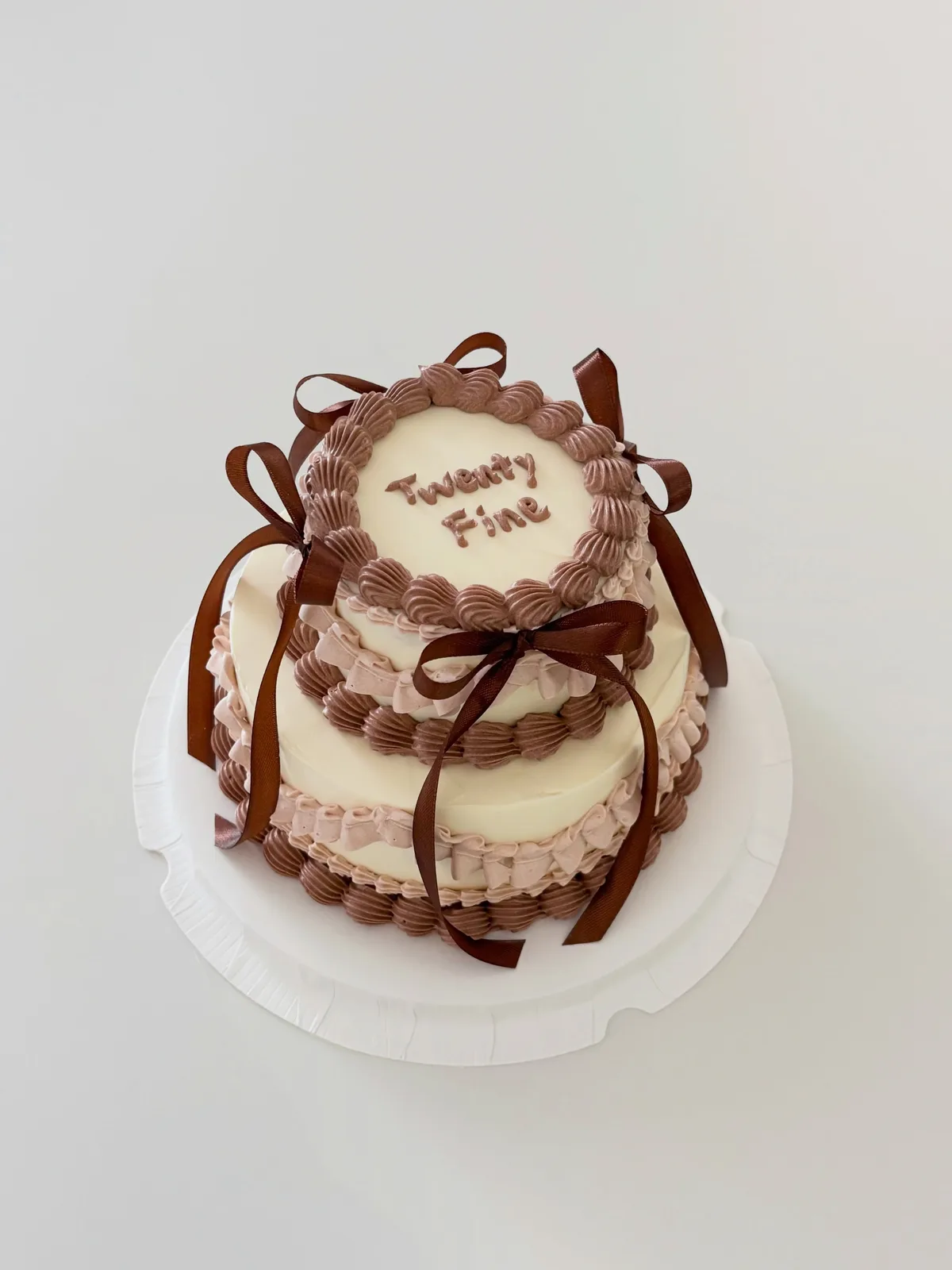 Ivory cake with chocolate brown ribbons and bows, bespoke celebration cake from Danine Cakes, South London