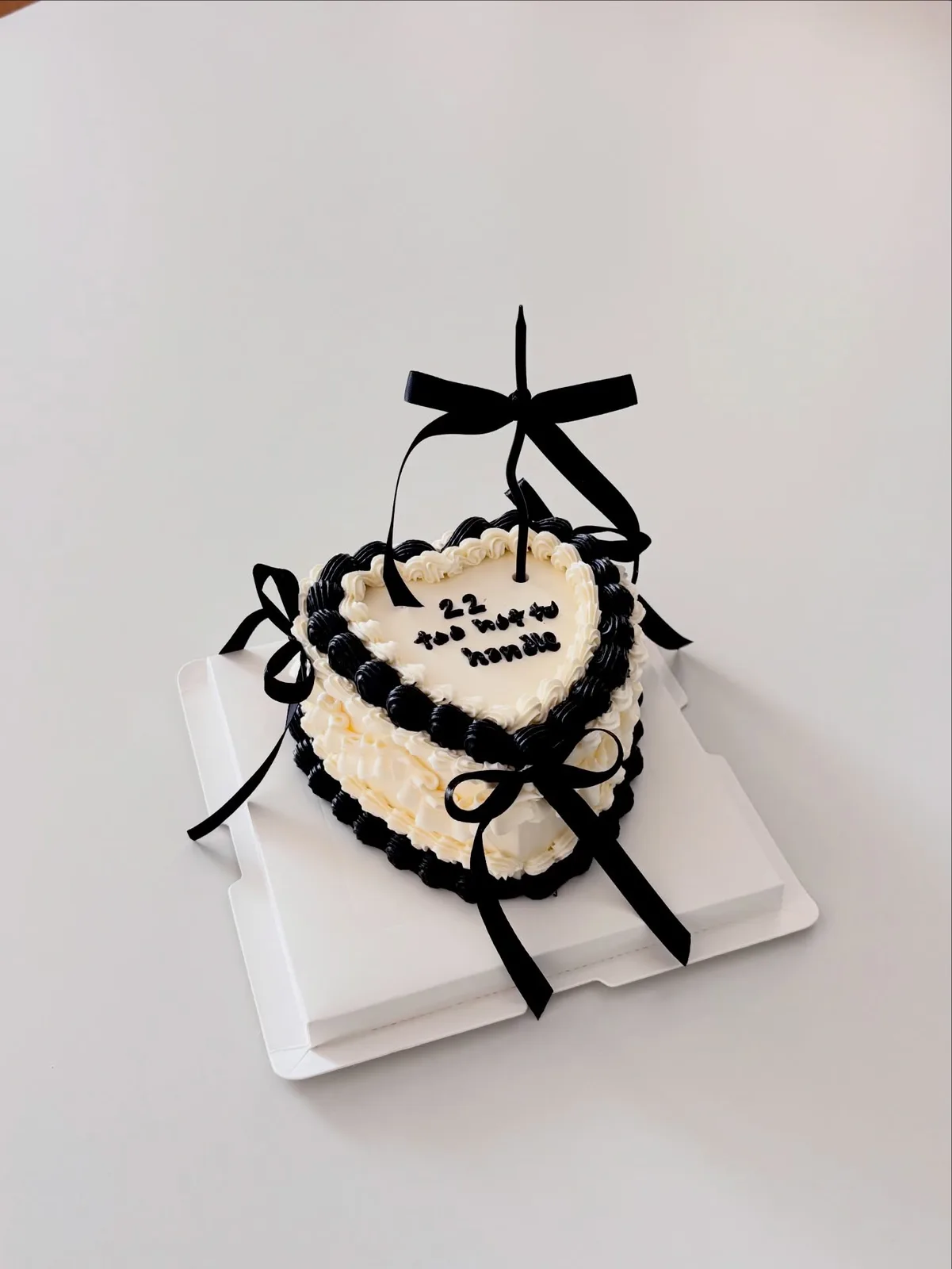 Ivory heart cake with black lace piping and bow, handmade to order by Danine Cakes in Streatham, South London