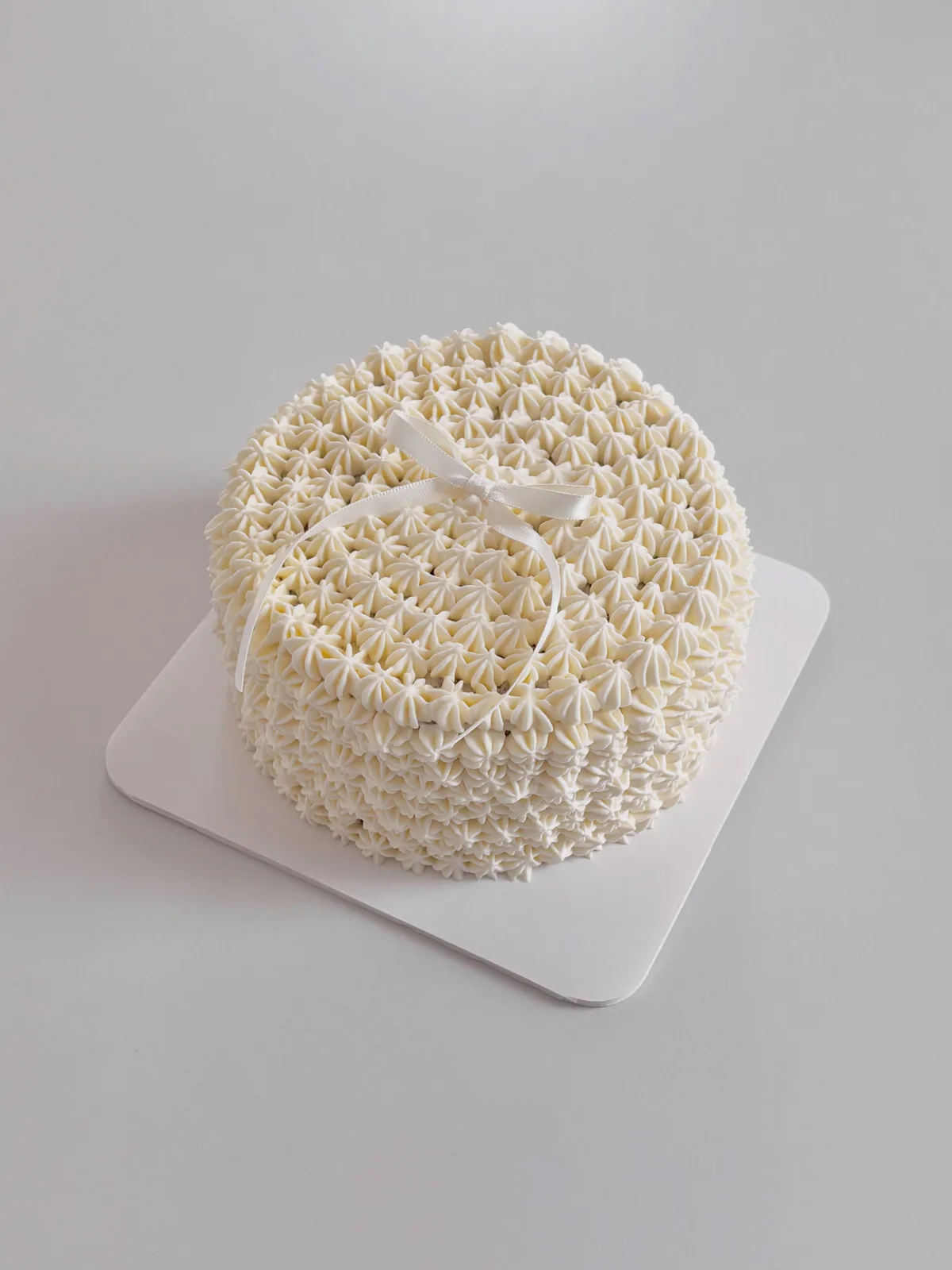 Ivory piped basketweave cake with bow, Korean-inspired custom cake handmade in Streatham, London