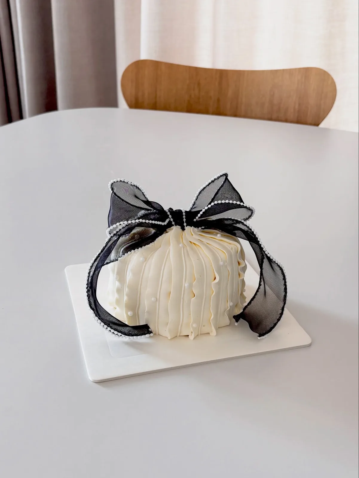 Ivory piped dome cake with black organza bow, handmade to order by Danine Cakes in Streatham, South London