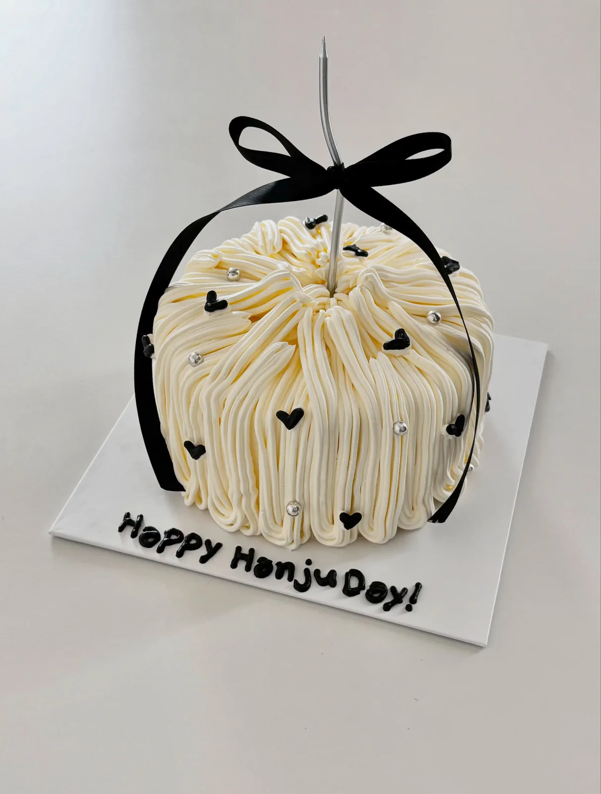 Ivory piped strand cake with black bow and hearts, handmade to order by Danine Cakes in Streatham, South London