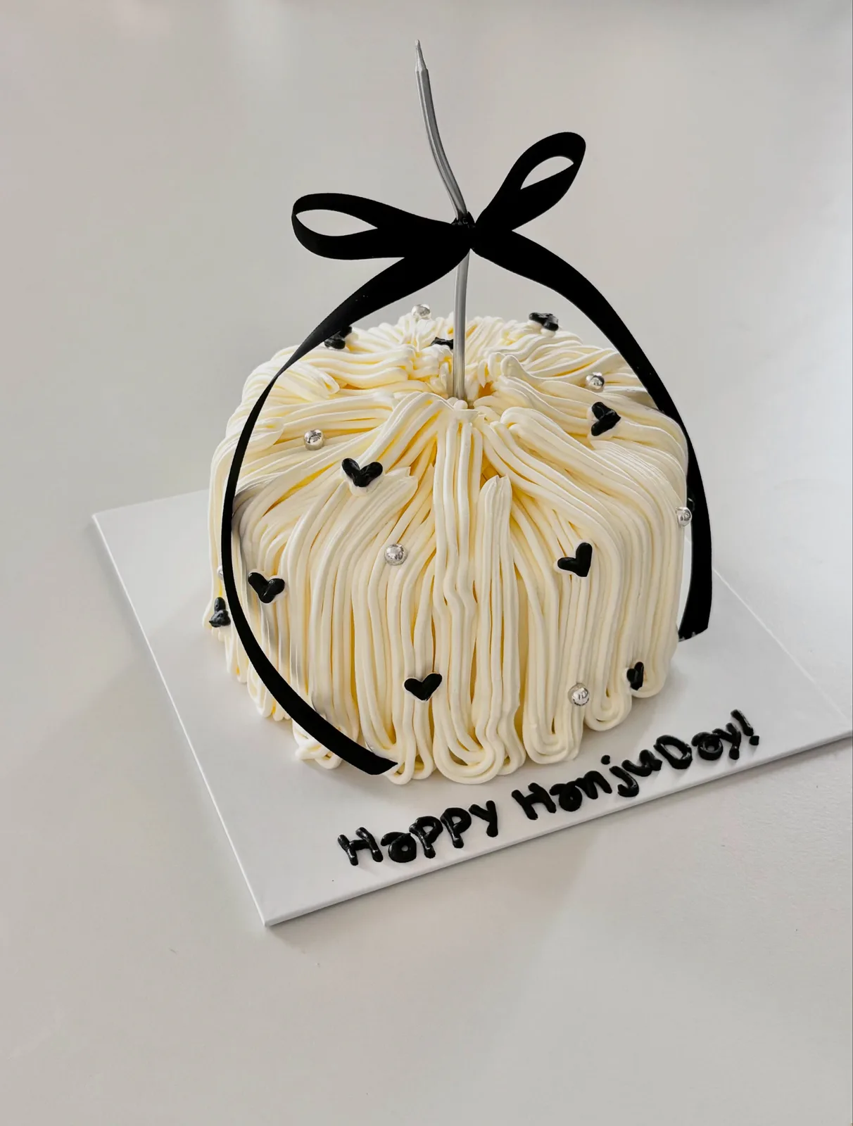 Ivory piped strand cake with black bow, bespoke celebration cake from Danine Cakes, South London
