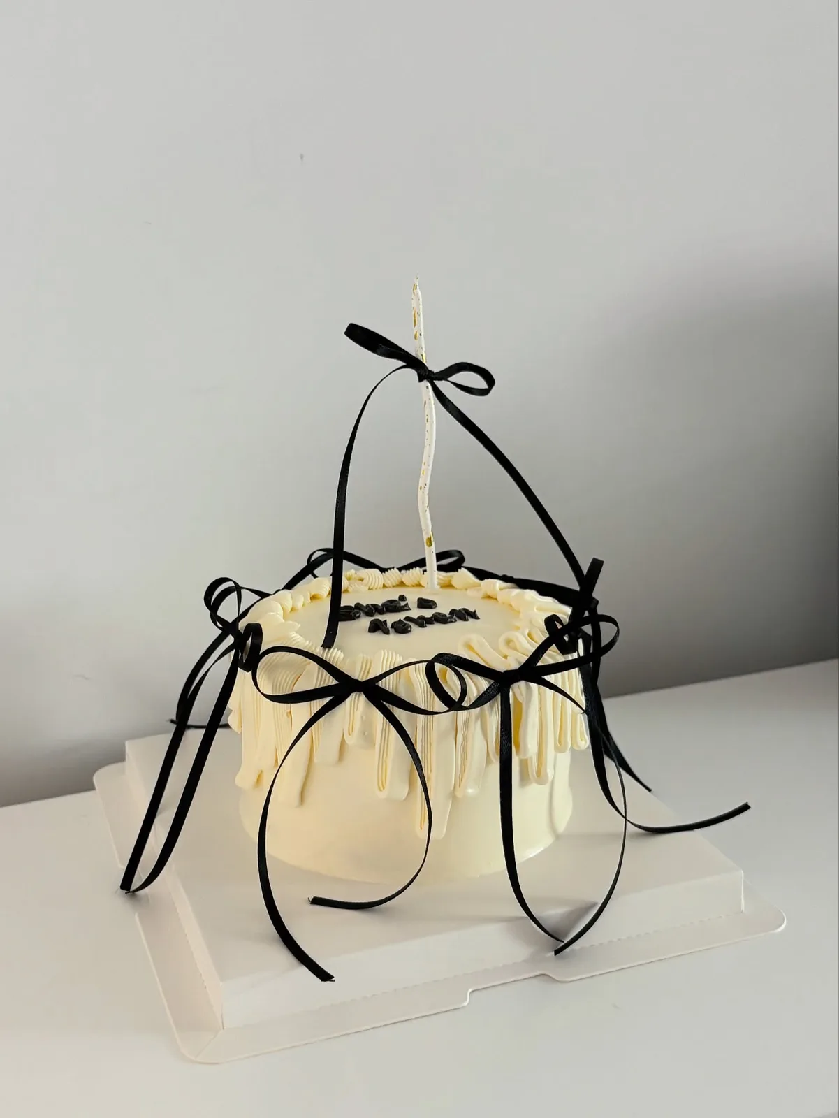 Ivory piped strand cake with black ribbon bow, handmade to order by Danine Cakes in Streatham, South London