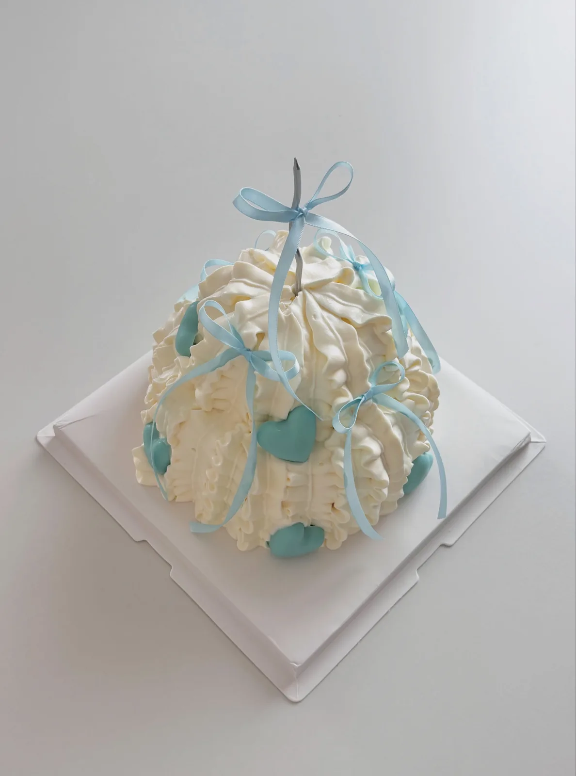 Ivory piped strand cake with blue ribbon bow, custom cake made in Streatham SW16 - Danine Cakes