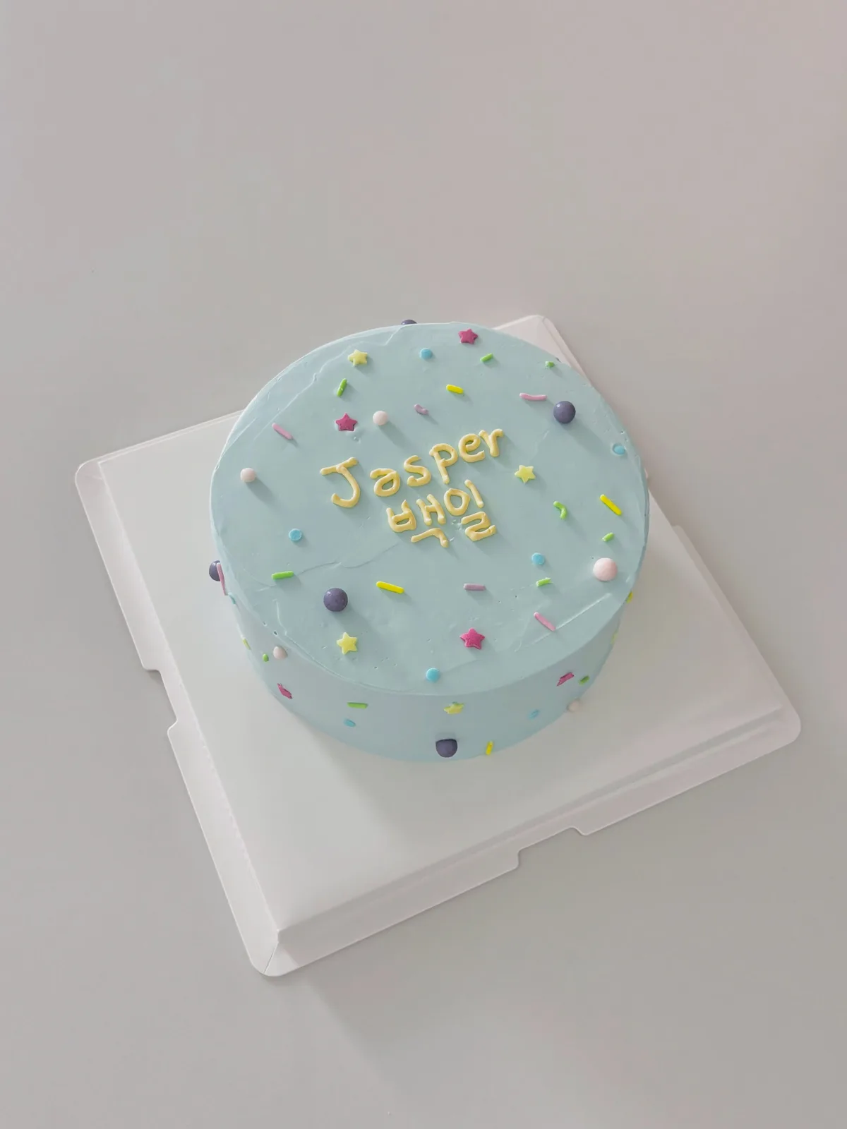 Pale blue cake with pastel confetti and lettering, bespoke celebration cake from Danine Cakes, South London