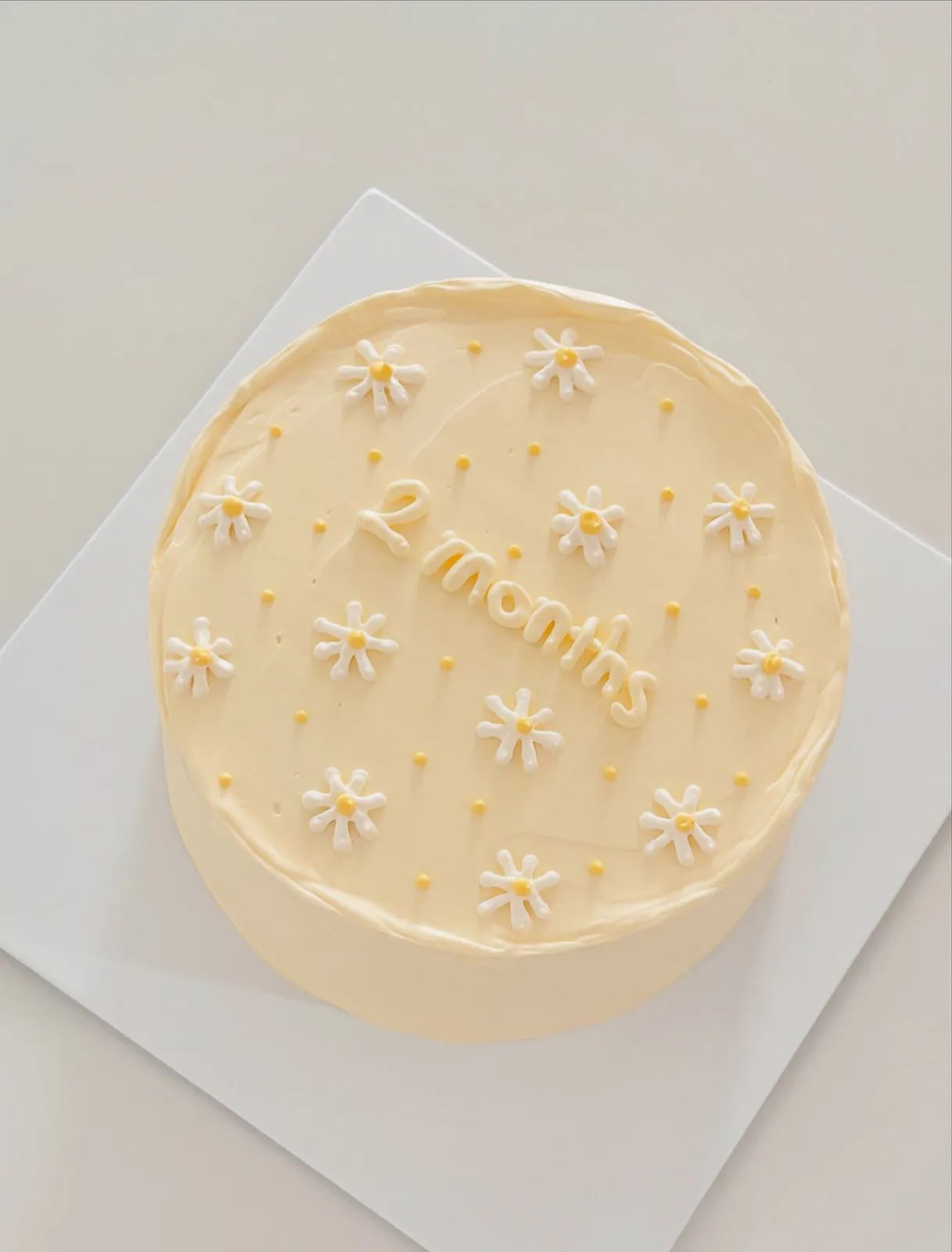 Pale yellow cake with white piped daisies, bespoke celebration cake from Danine Cakes, South London