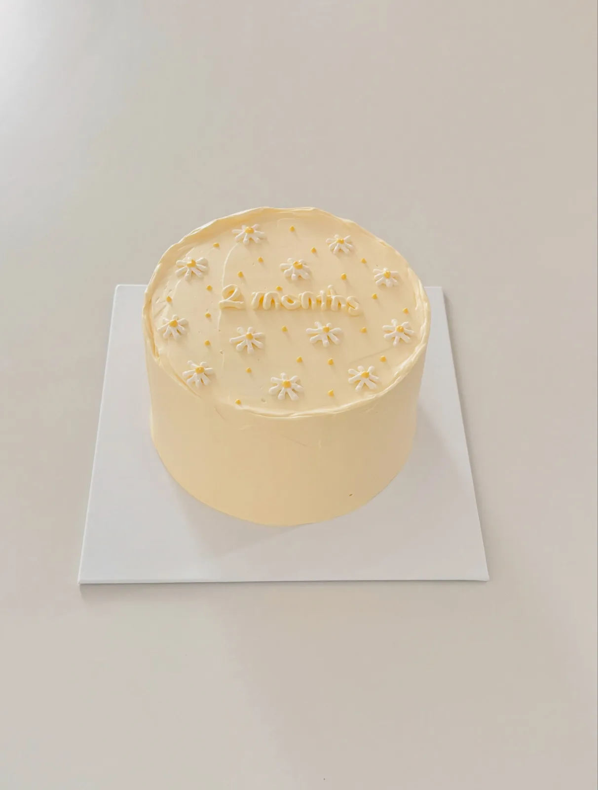 Pale yellow cake with white piped daisies, custom cake made in Streatham SW16 - Danine Cakes