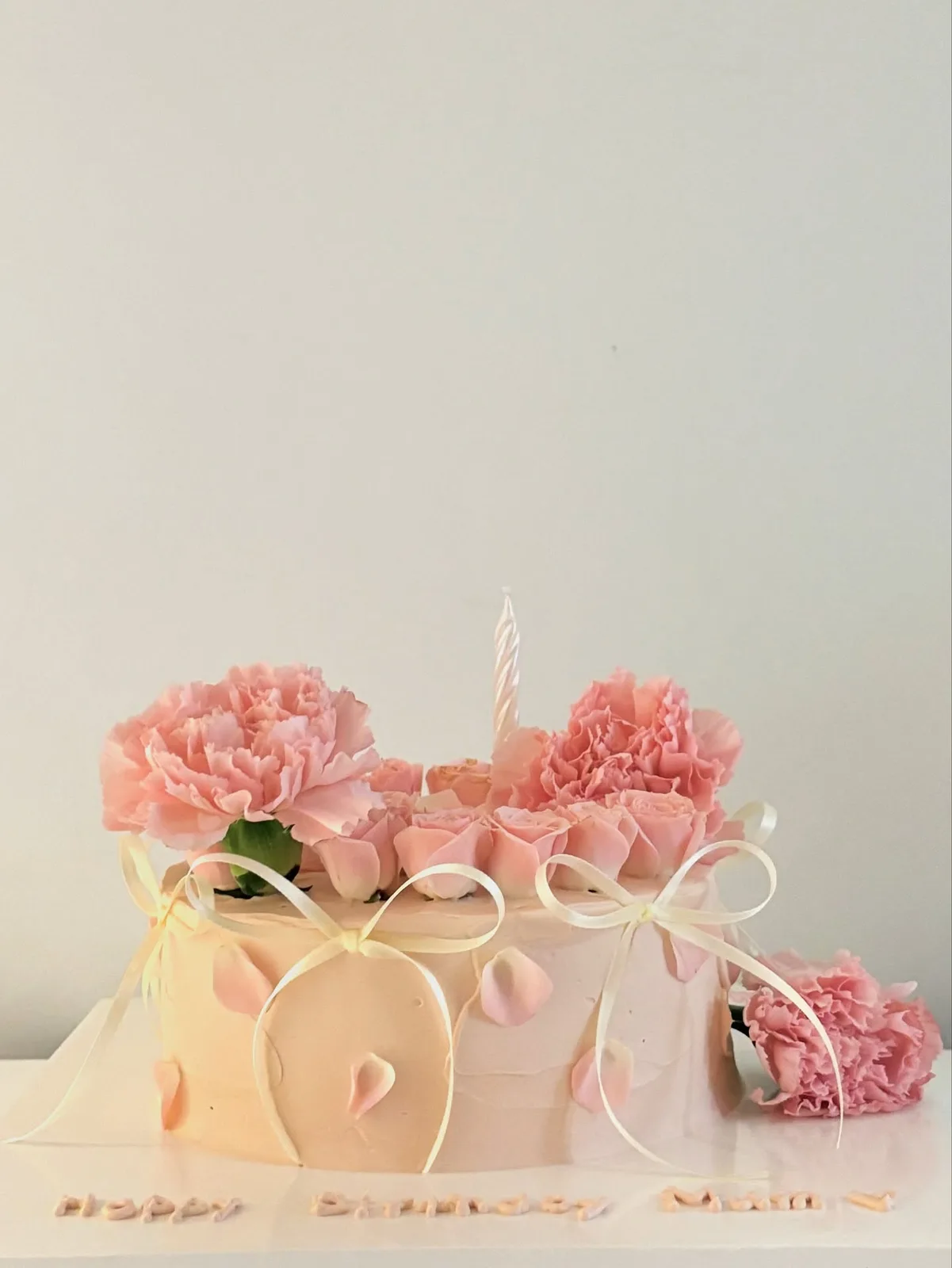 Peach cake with fresh carnations and candles, bespoke celebration cake from Danine Cakes, South London