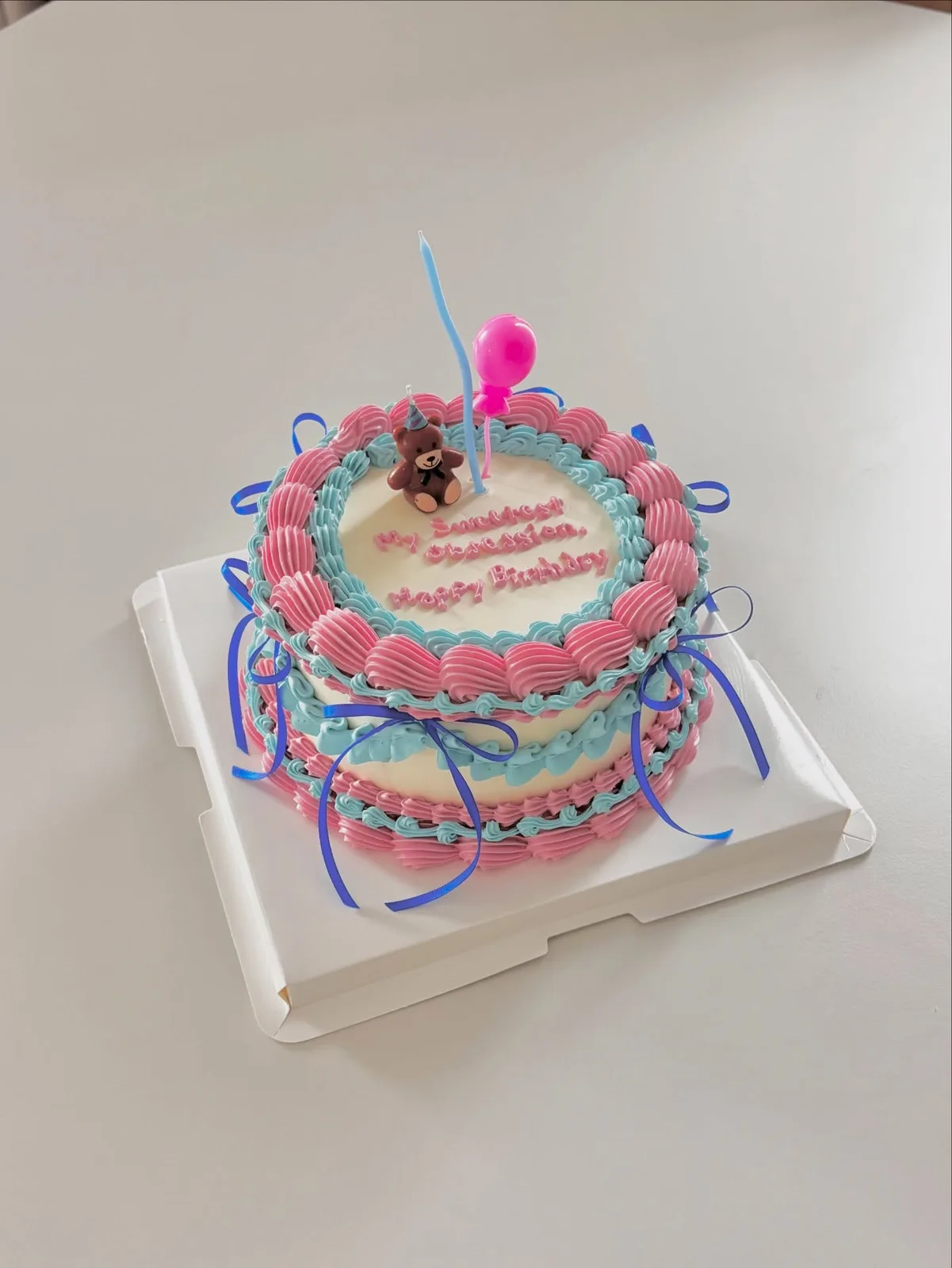Pink and blue cake with ribbons and piped border, handmade to order by Danine Cakes in Streatham, South London