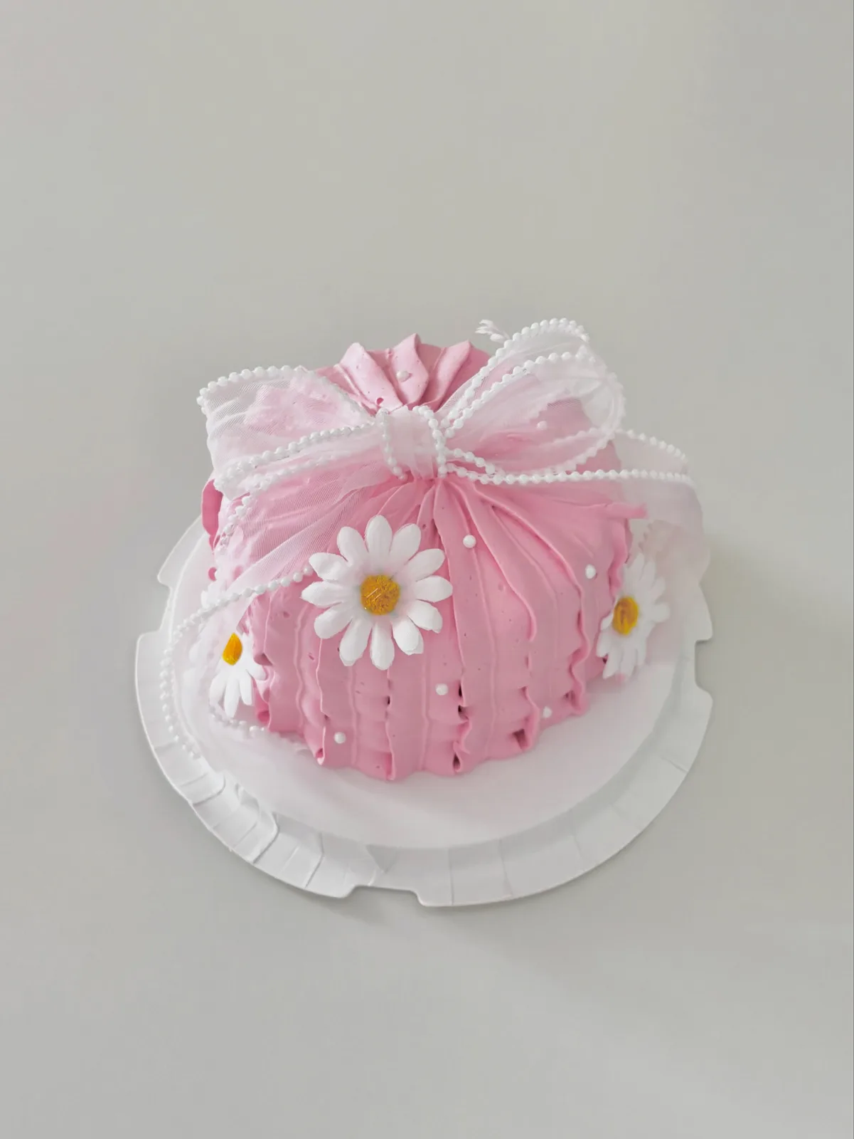 Pink cake with white lace piping, daisy and pink bow, custom cake made in Streatham SW16 - Danine Cakes
