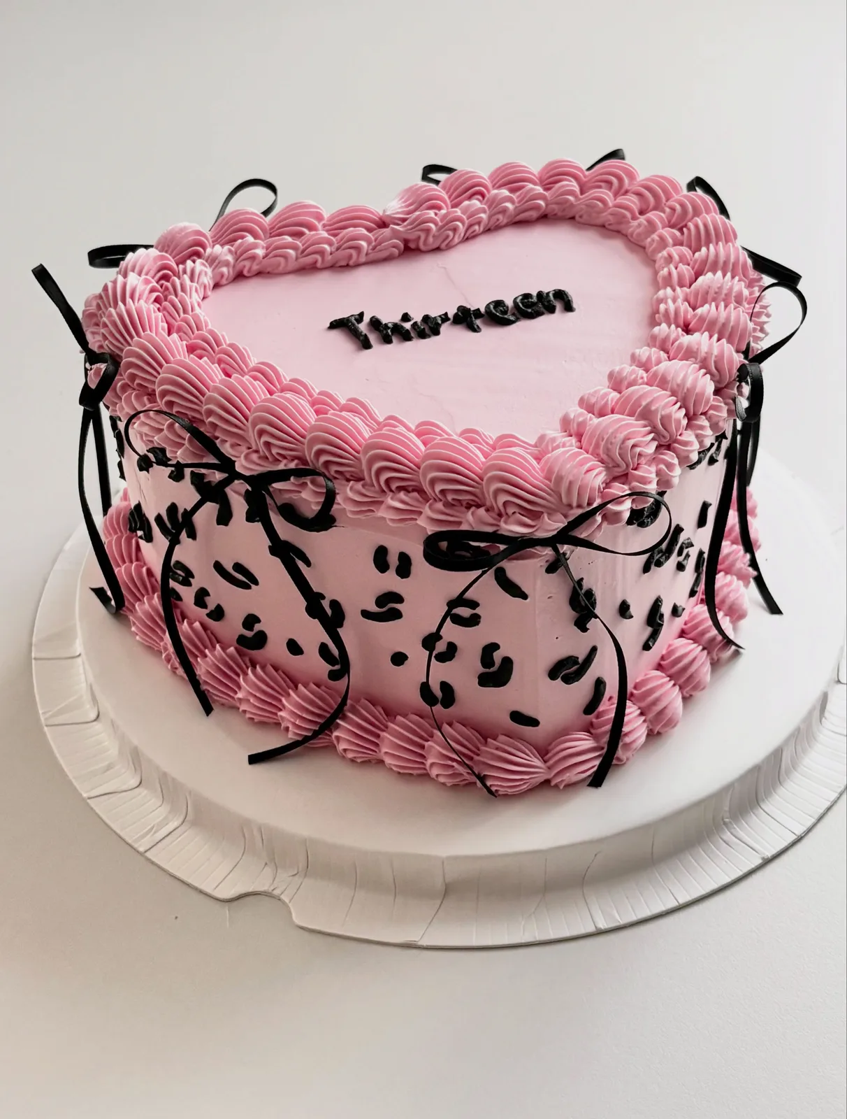 Pink heart cake with black bows and leopard piping, handmade to order by Danine Cakes in Streatham, South London