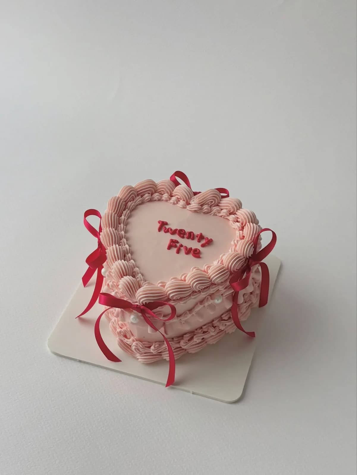 Pink heart cake with red ribbons and lace piping, handmade to order by Danine Cakes in Streatham, South London