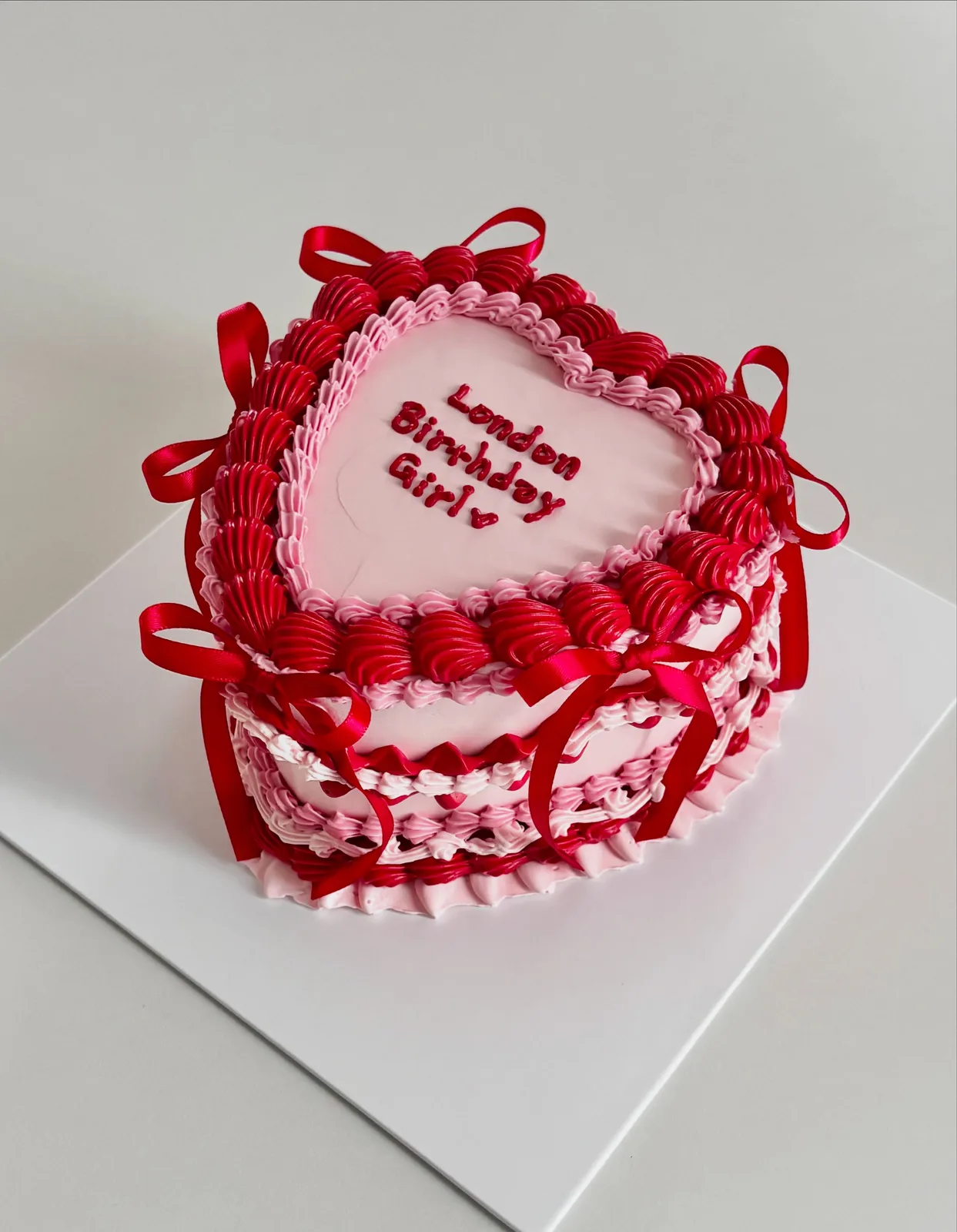 Red heart cake with ribbons and piped lace border, bespoke celebration cake from Danine Cakes, South London