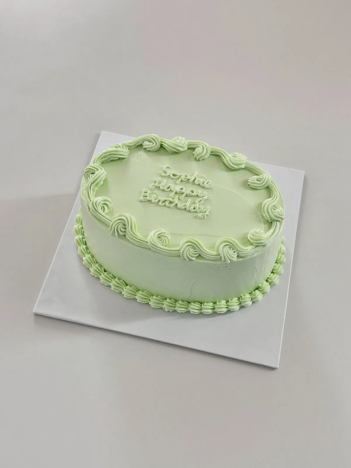 Sage green cake with piped scroll border, handmade to order by Danine Cakes in Streatham, South London