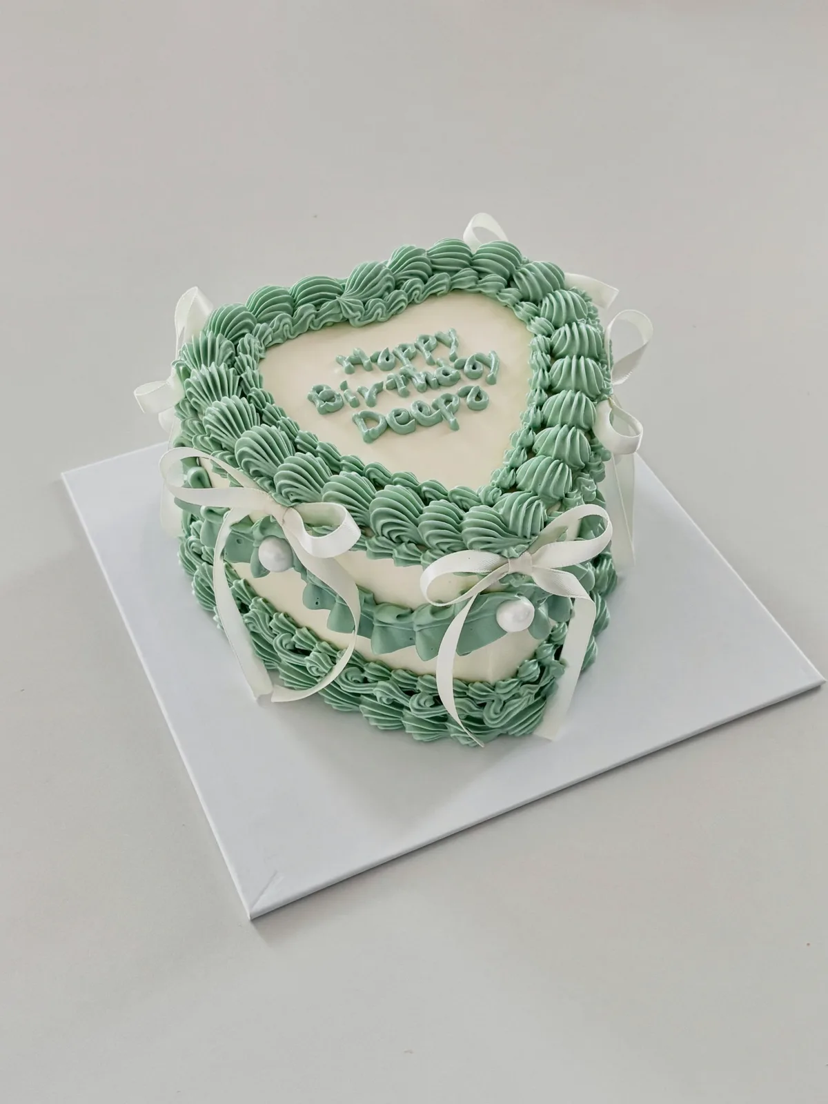 Sage green heart cake with white ribbon bows, custom cake made in Streatham SW16 - Danine Cakes