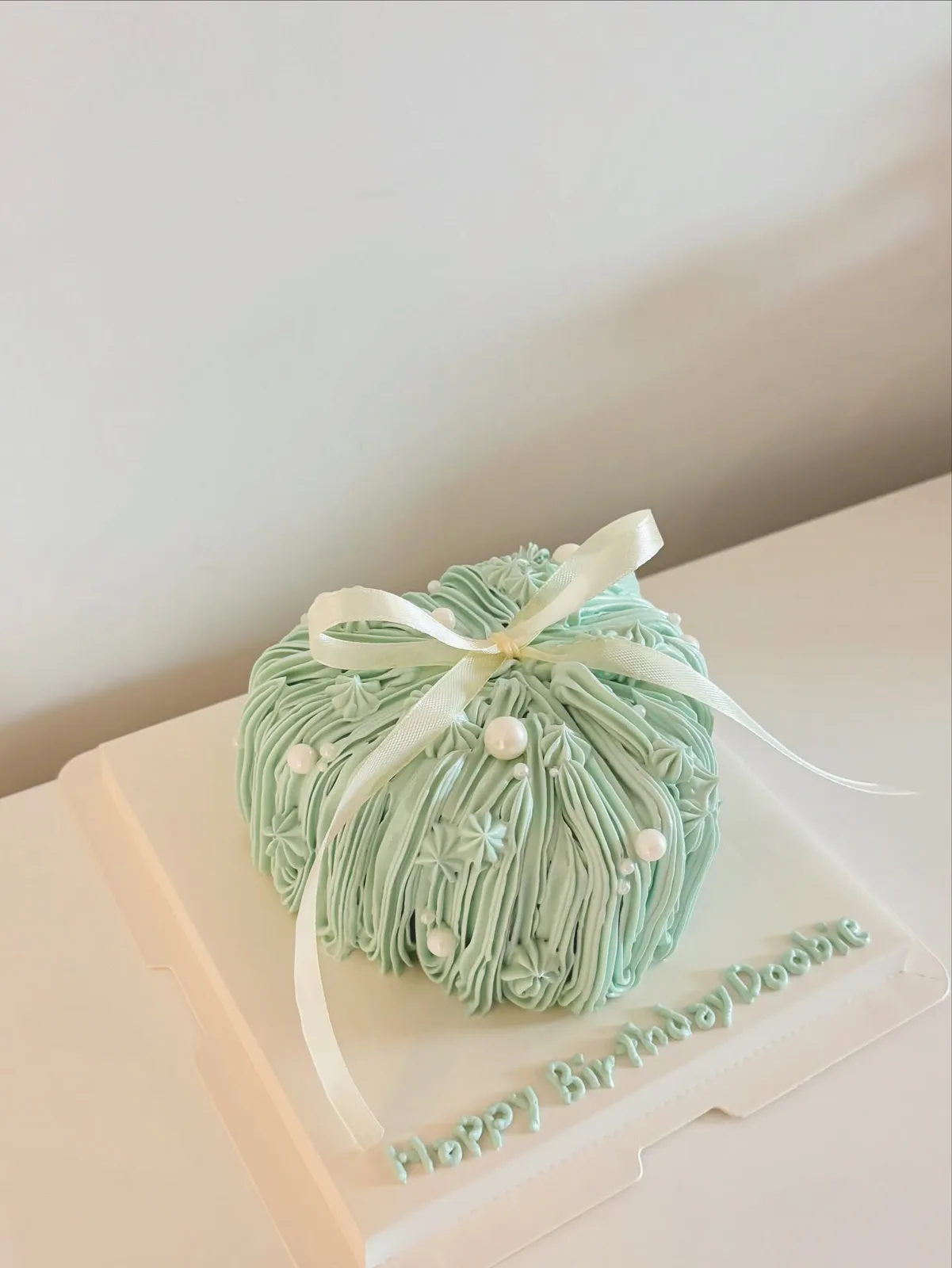 Sage green piped dome cake with pearls, handmade to order by Danine Cakes in Streatham, South London