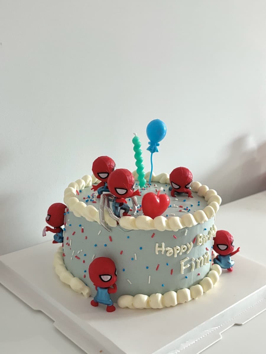 Spiderman swings onto a blue birthday cake
