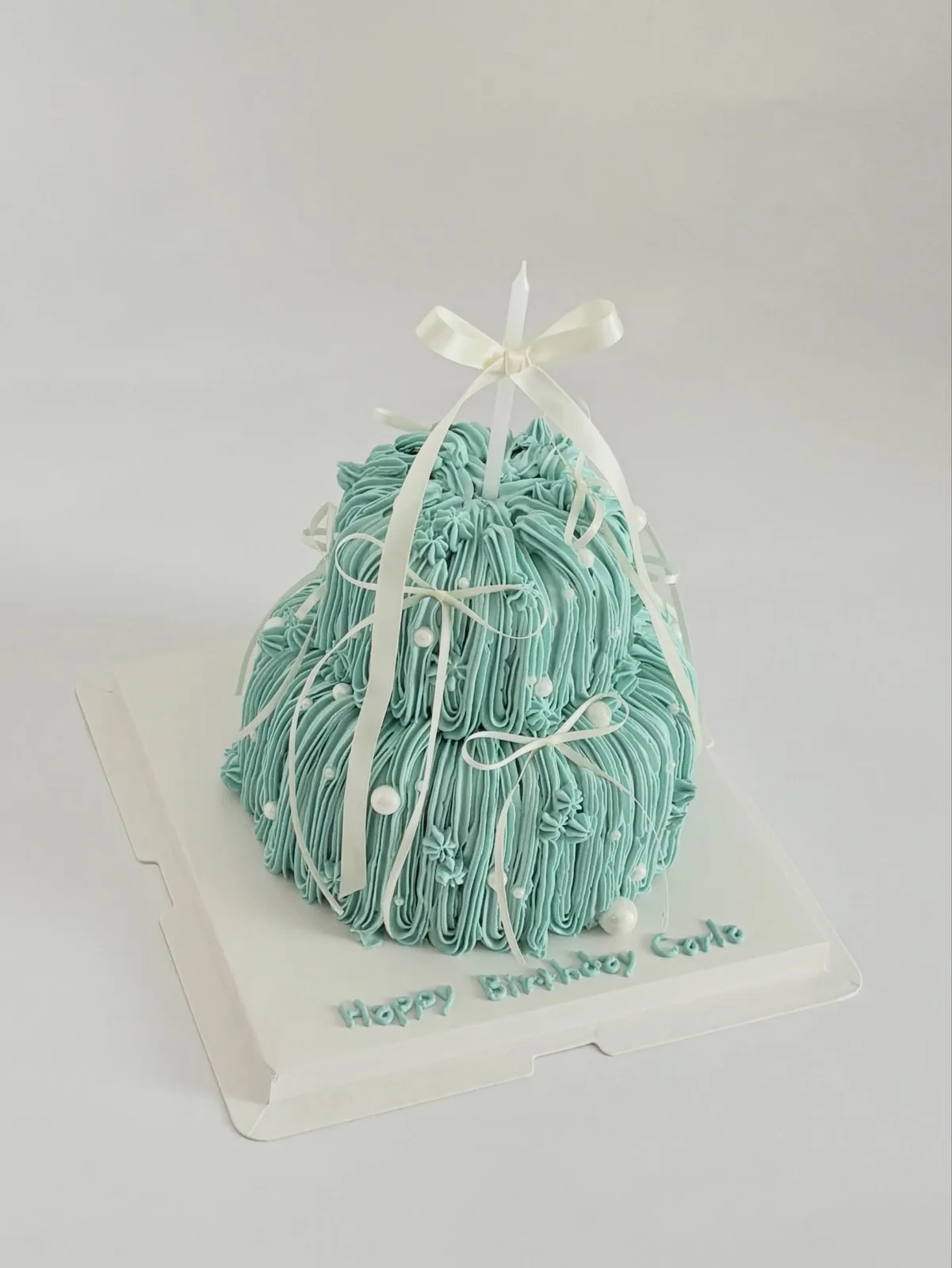 Teal piped strand cake with white ribbon bow, custom cake made in Streatham SW16 - Danine Cakes