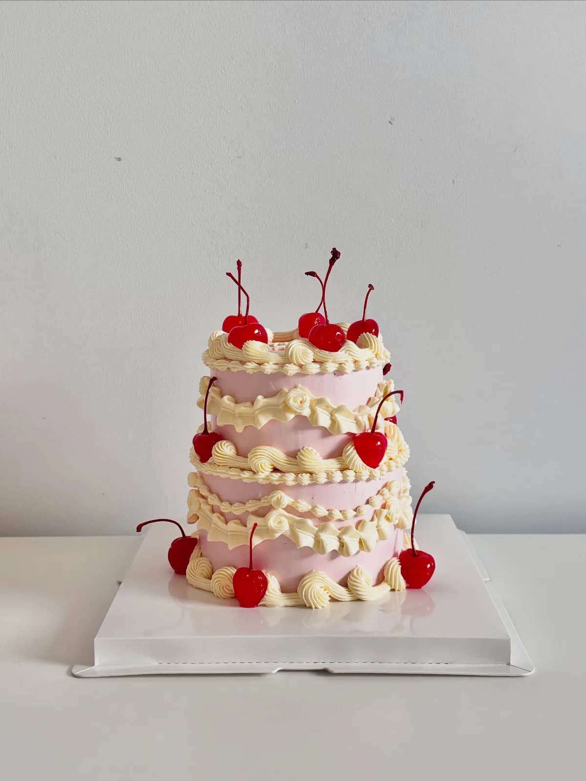 Three tier cream cake with cherries and piped shells, bespoke celebration cake from Danine Cakes, South London