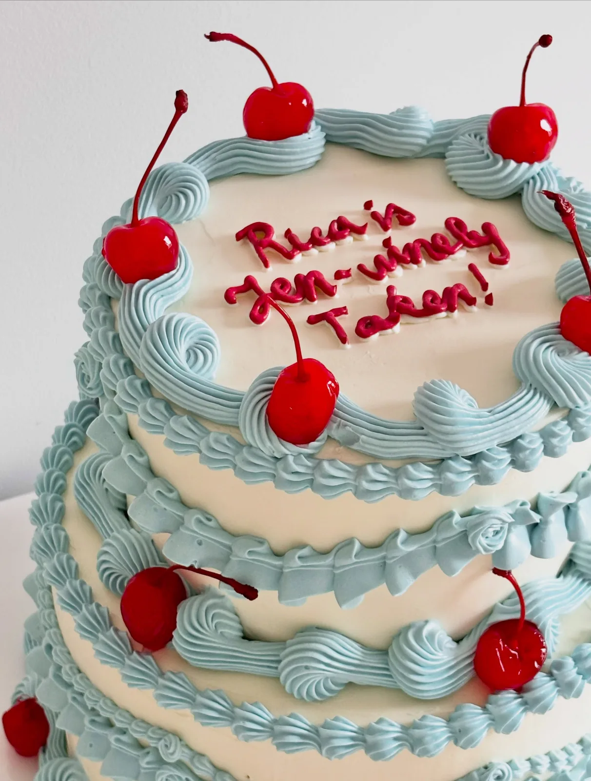 Two tier blue cake with glace cherries and piped scrolls, bespoke celebration cake from Danine Cakes, South London