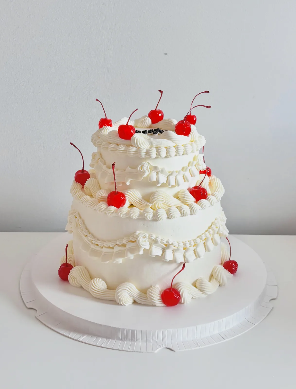 Two tier white cake with cherries and piped shells, bespoke celebration cake from Danine Cakes, South London