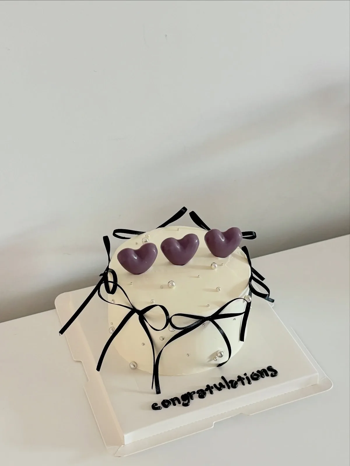 White cake with black bows and purple hearts, custom cake made in Streatham SW16 - Danine Cakes