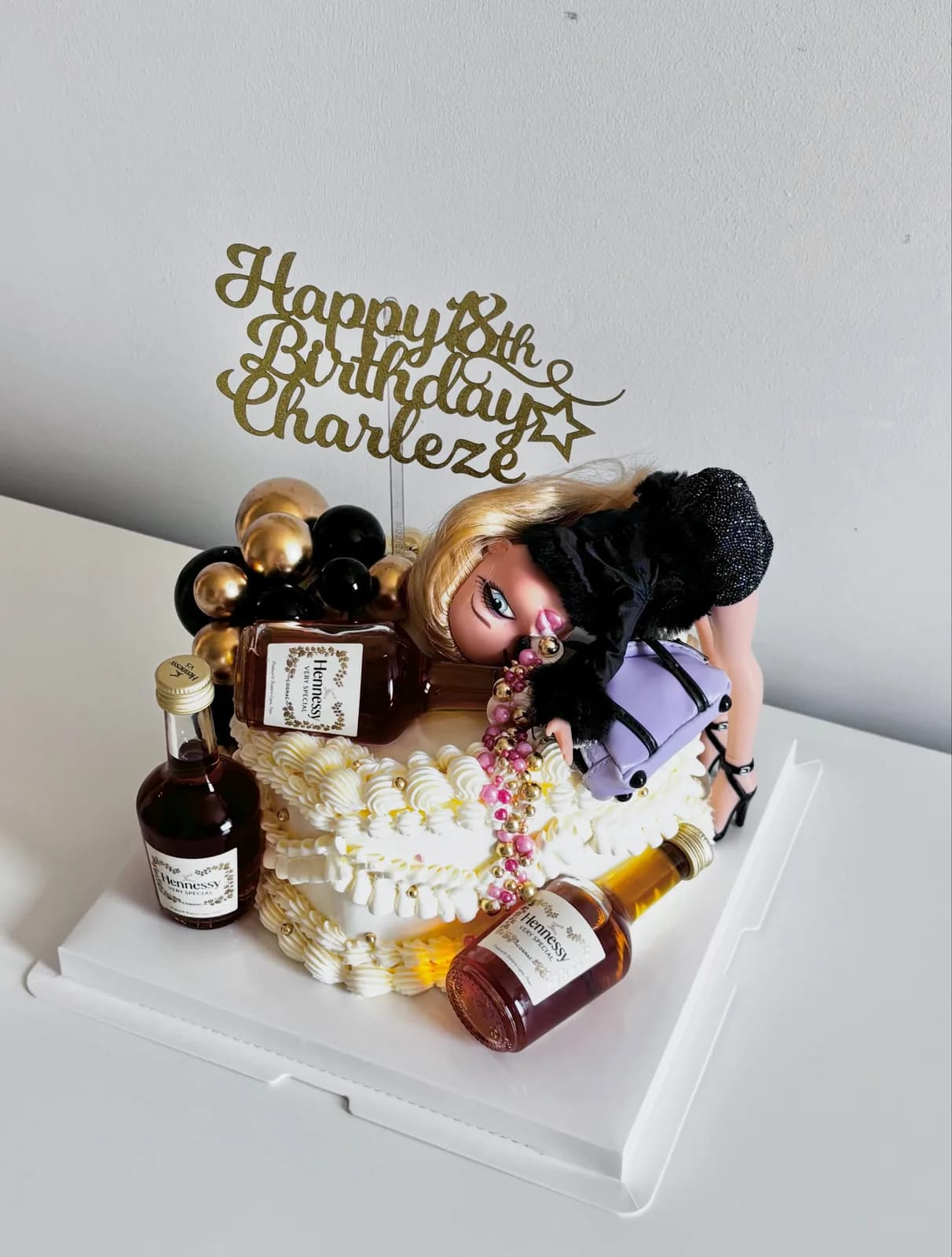 White cake with novelty bottle and figure toppers, handmade to order by Danine Cakes in Streatham, South London
