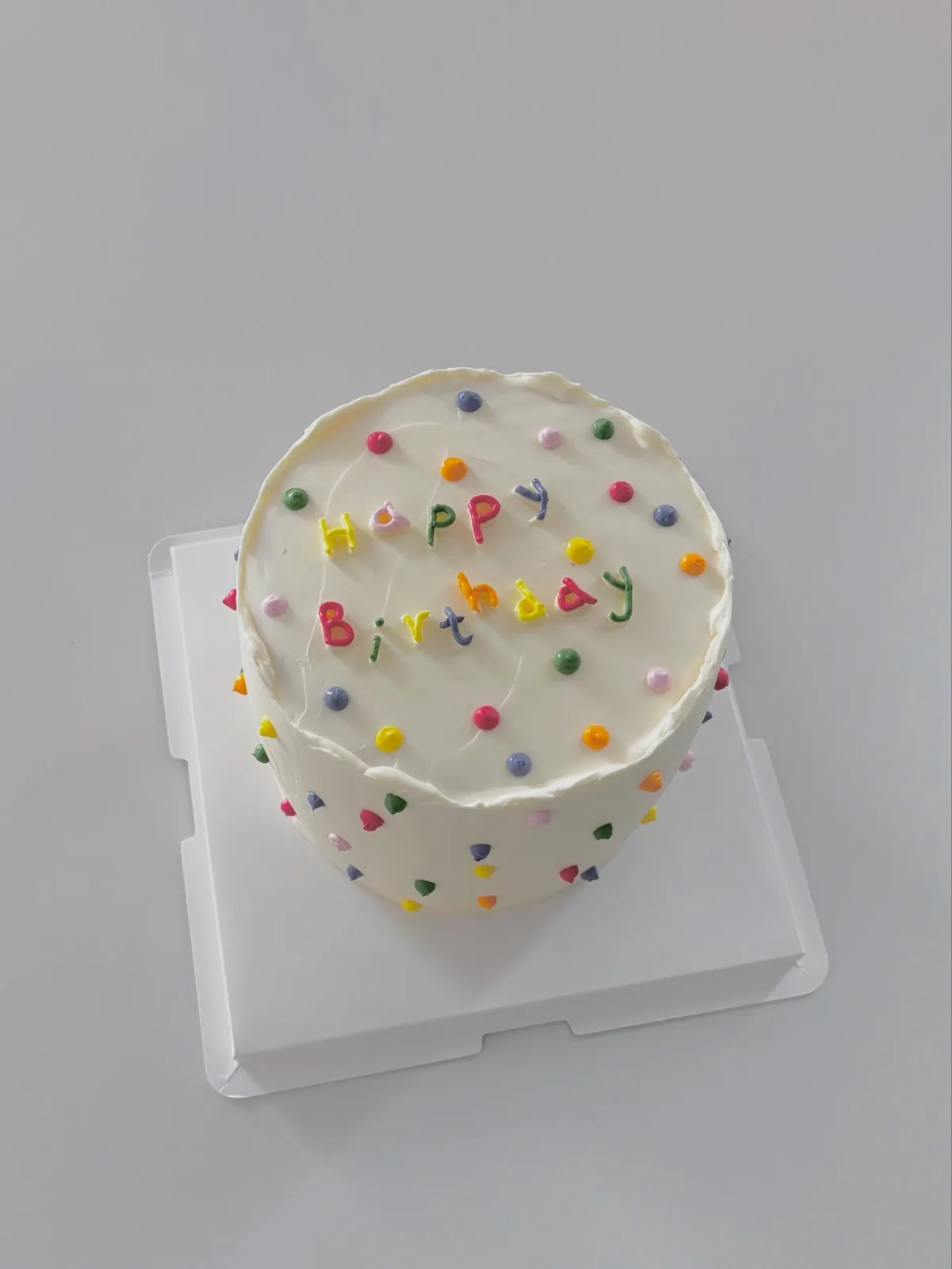 White cake with rainbow confetti and piped lettering, bespoke celebration cake from Danine Cakes, South London