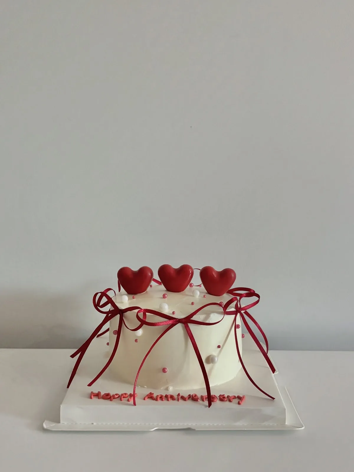 White cake with red hearts and ribbons, bespoke celebration cake from Danine Cakes, South London