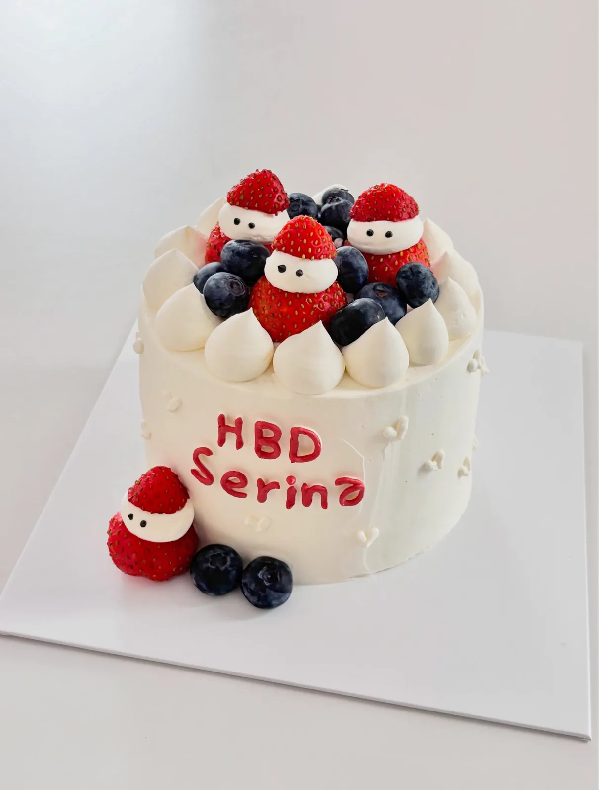 White cake with strawberries, blueberries and Santa figures, bespoke celebration cake from Danine Cakes, South London