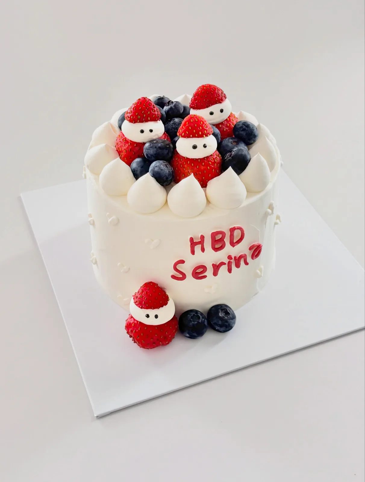 White cake with strawberries, blueberries and Santa figures, handmade to order by Danine Cakes in Streatham, South London