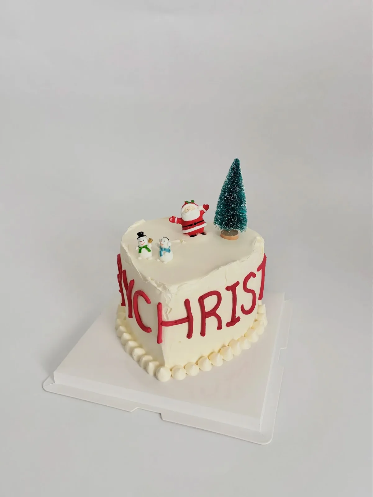 White Christmas cake with Santa and tree toppers, bespoke celebration cake from Danine Cakes, South London