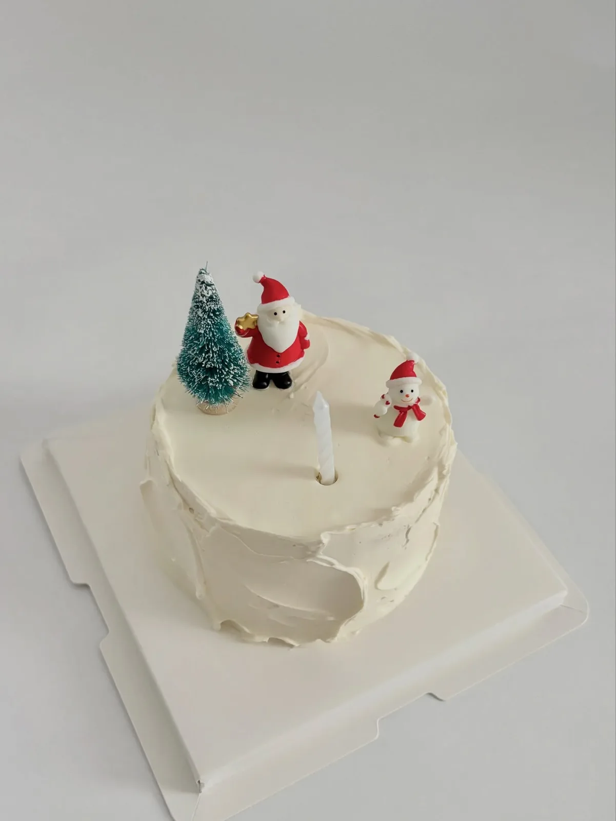White Christmas cake with Santa and tree toppers, handmade to order by Danine Cakes in Streatham, South London