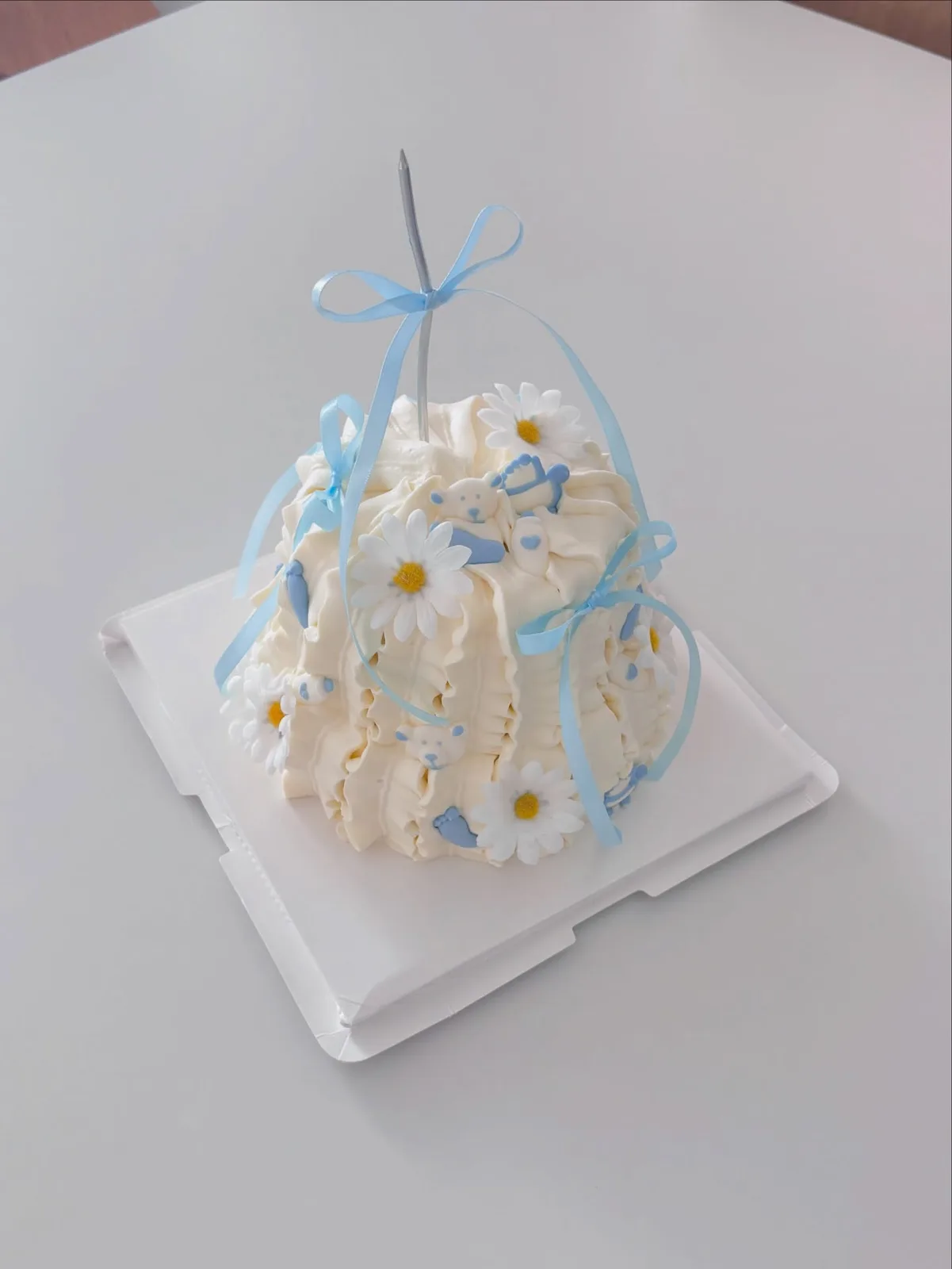 White piped cake with daisies and blue ribbon, Korean-inspired custom cake handmade in Streatham, London