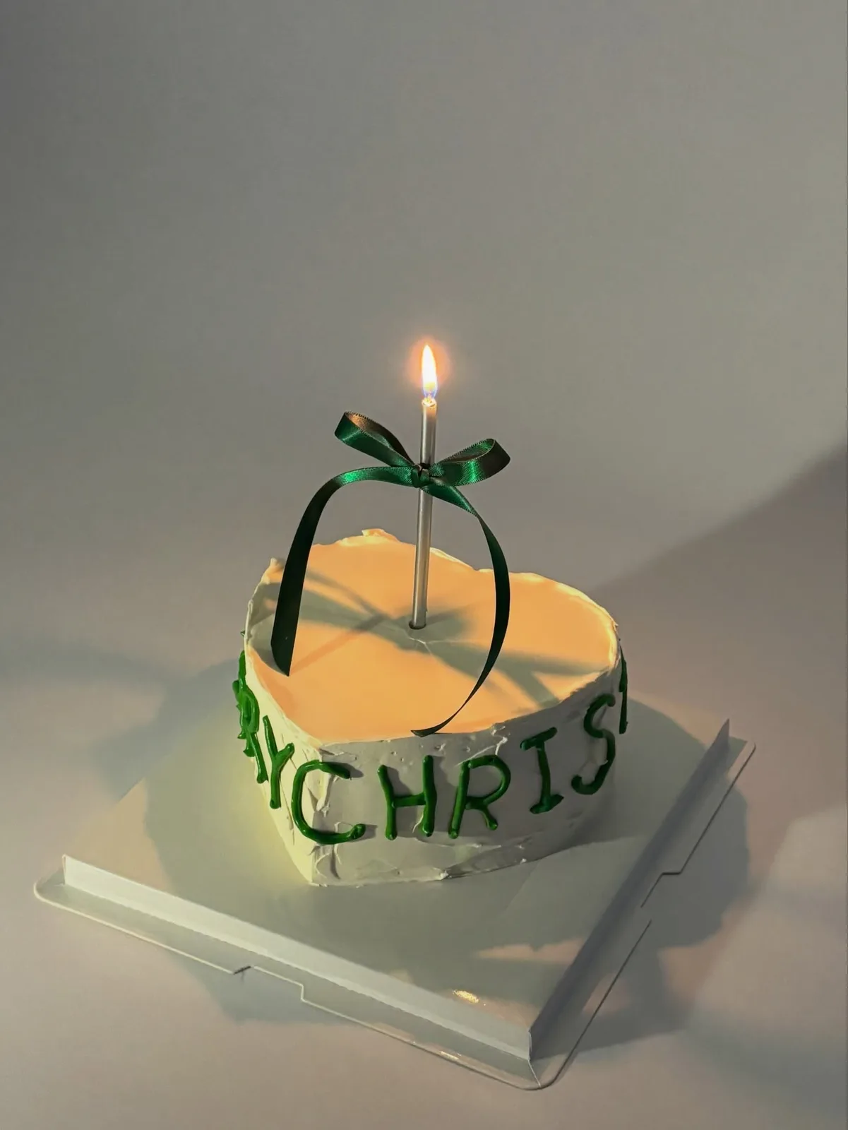Yellow cake with green bow and lit candle, handmade to order by Danine Cakes in Streatham, South London