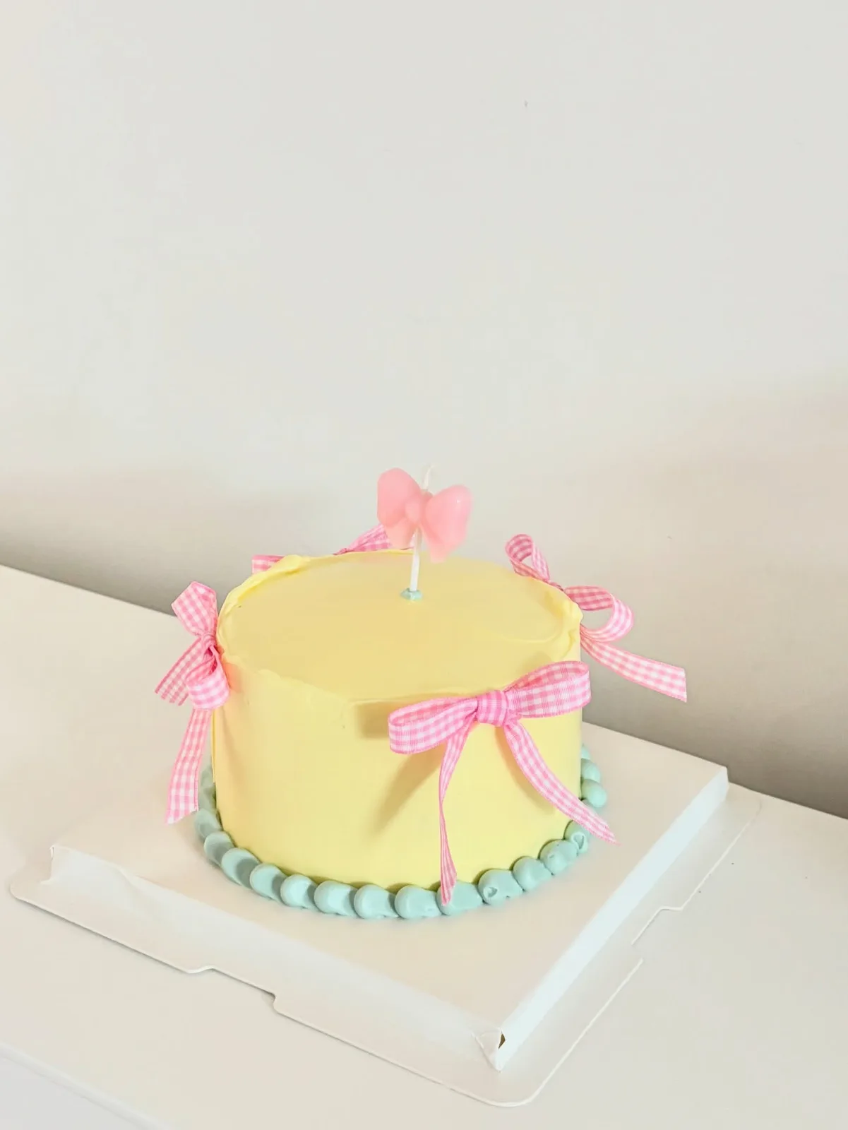 Yellow cake with pink gingham bows and mint border, bespoke celebration cake from Danine Cakes, South London