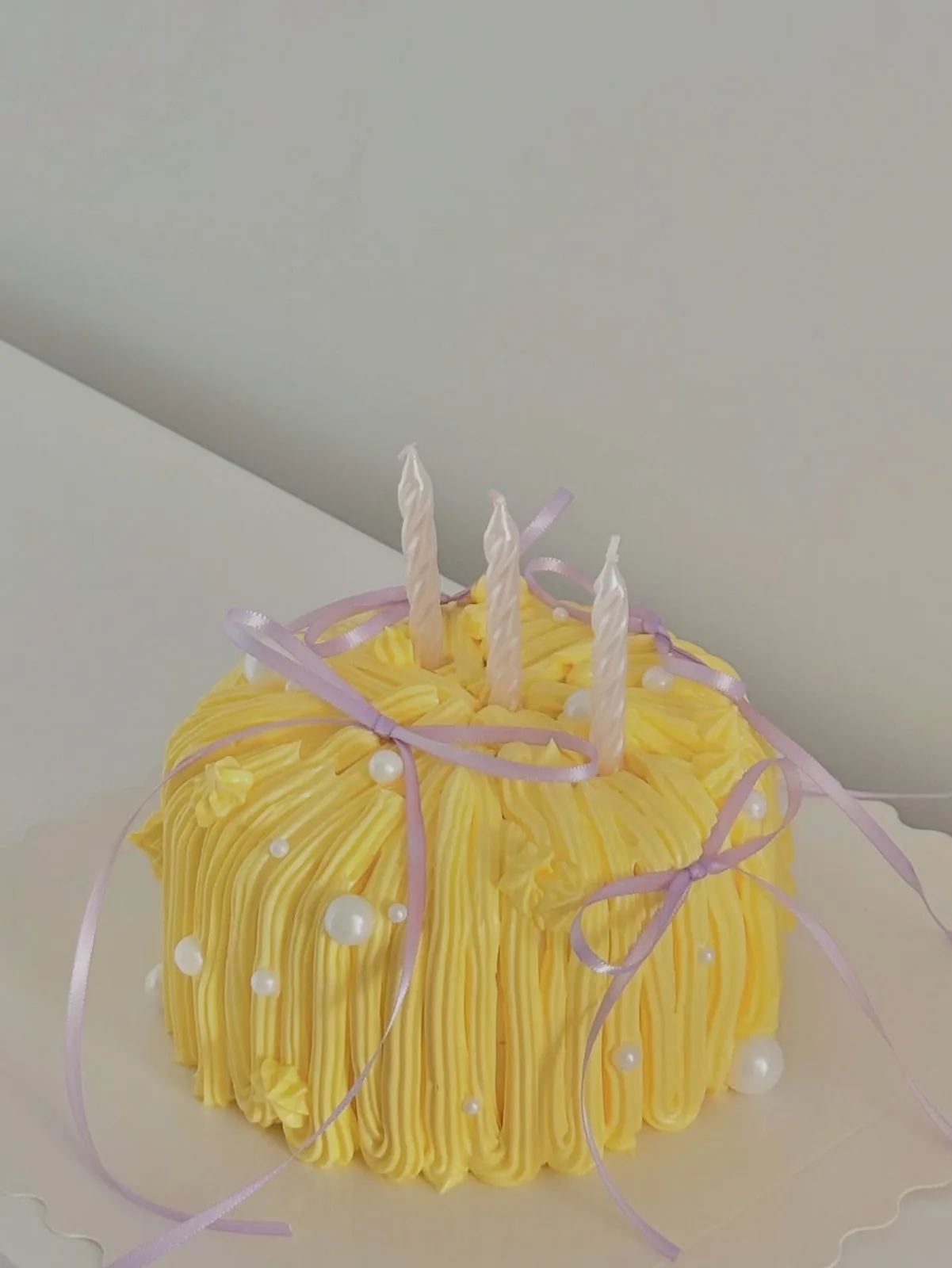 Yellow piped strand cake with lilac ribbons and candles, bespoke celebration cake from Danine Cakes, South London