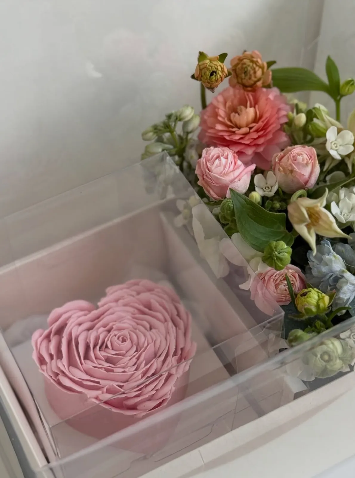 Pink heart-shaped rose cake by Danine Cakes in a gift box beside a fresh flower bouquet by Barley Flower Studio